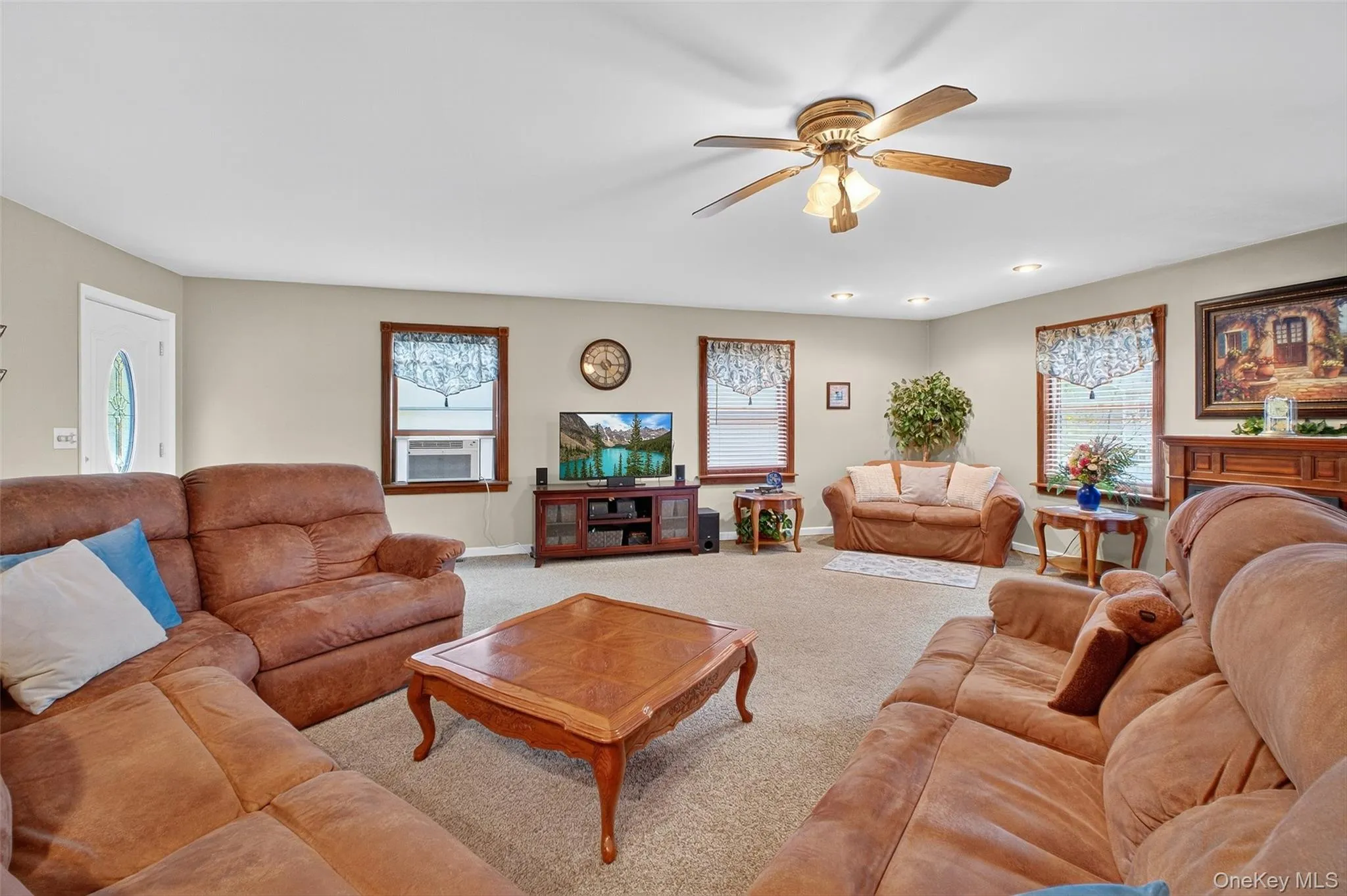 Carpeted living area with plenty of natural light, a ceiling fan, and cooling unit Carpeted living area with plenty of natural light, a ceiling fan, and cooling unit