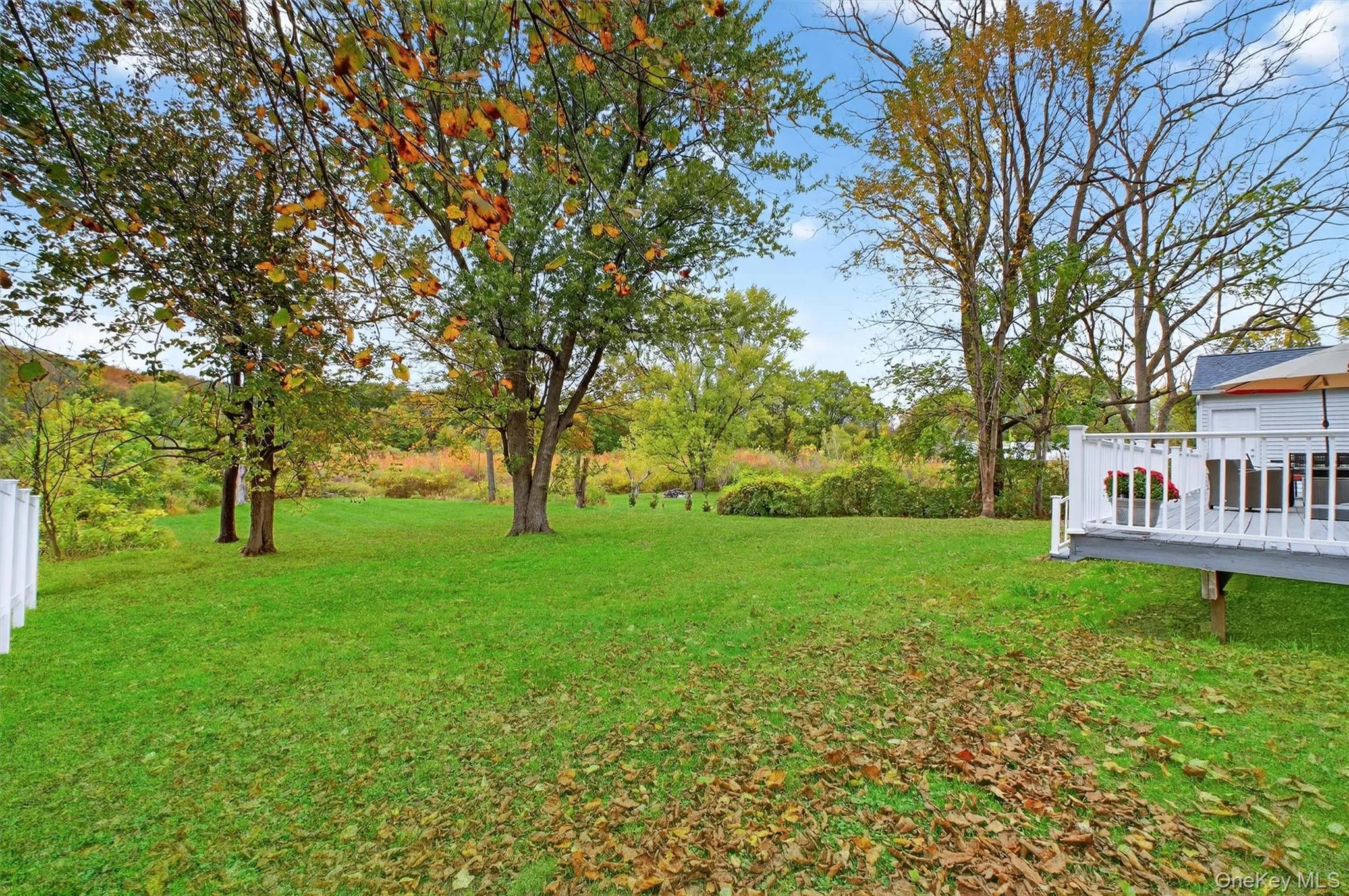 View of green lawn featuring a deck View of green lawn featuring a deck