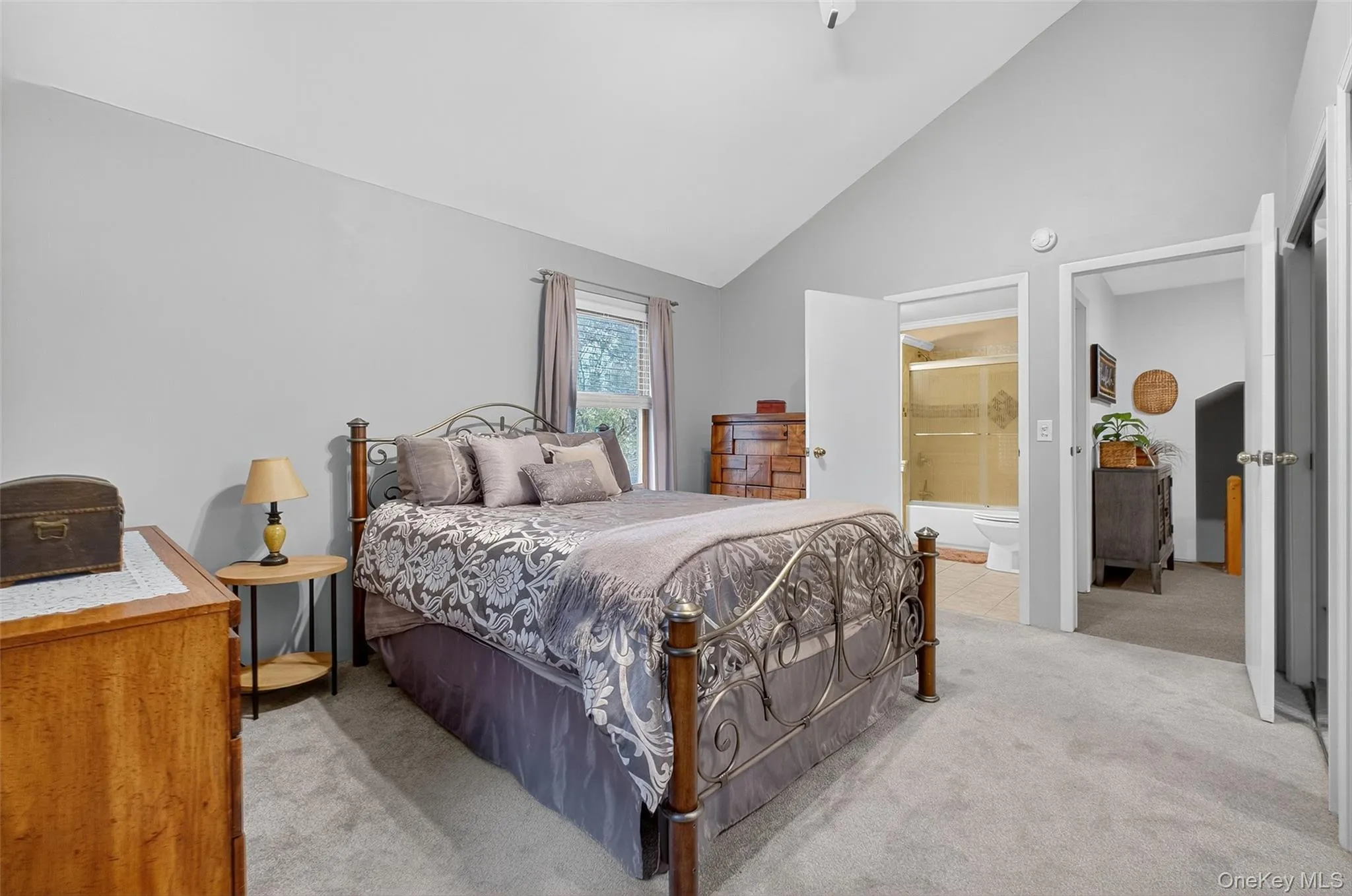 Bedroom featuring light carpet, ceiling fan, high vaulted ceiling, and connected bathroom Bedroom featuring light carpet, ceiling fan, high vaulted ceiling, and connected bathroom