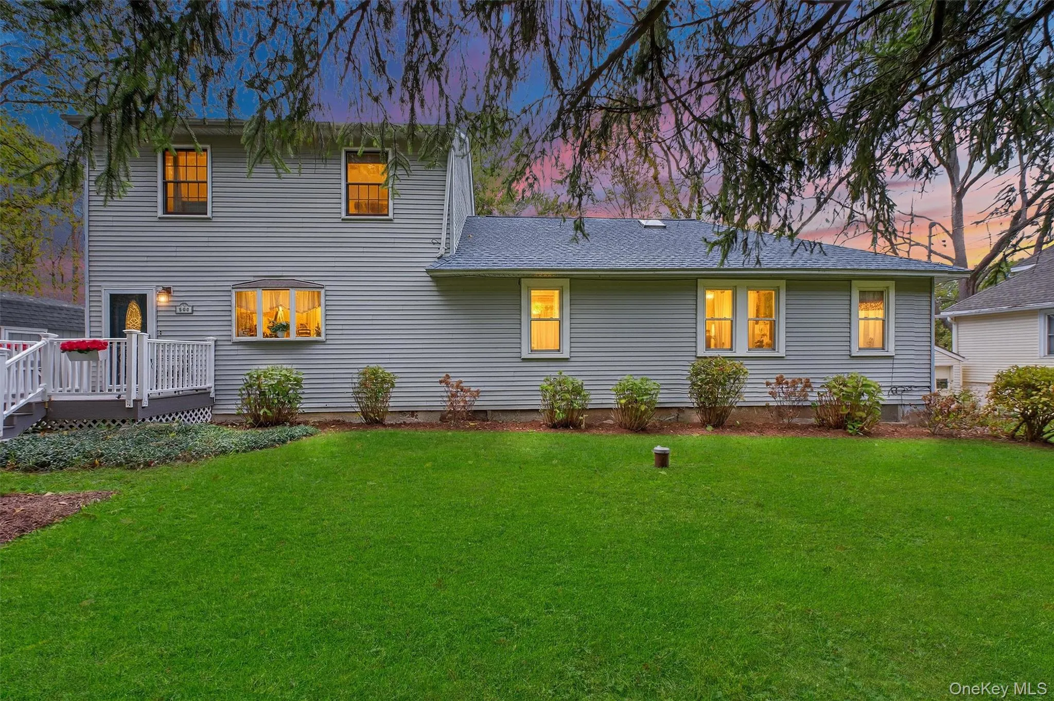 Rear view of property with a lawn, a wooden deck, and roof with shingles Rear view of property with a lawn, a wooden deck, and roof with shingles