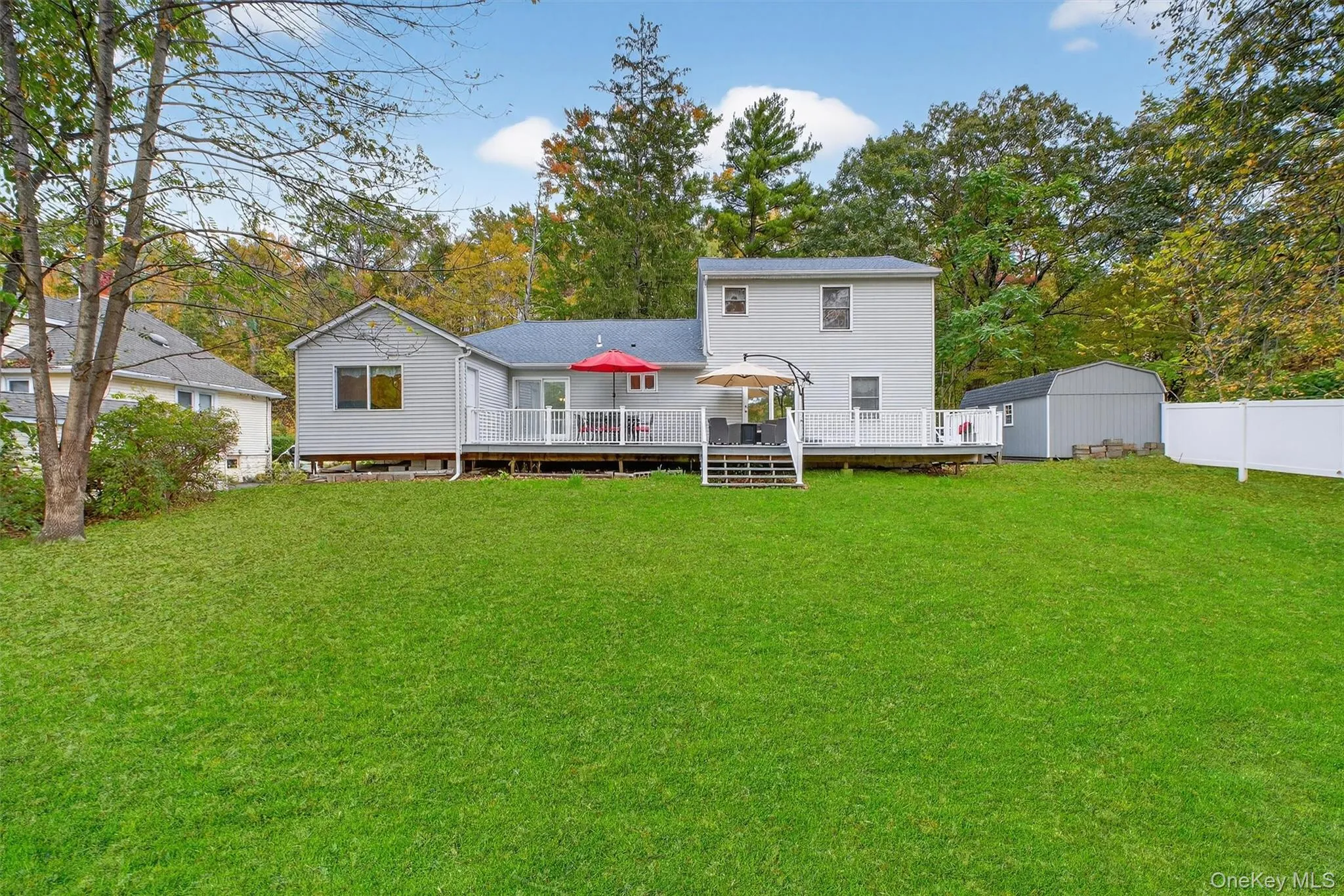 Rear view of house with a deck, view of wooded area, and a storage shed Rear view of house with a deck, view of wooded area, and a storage shed