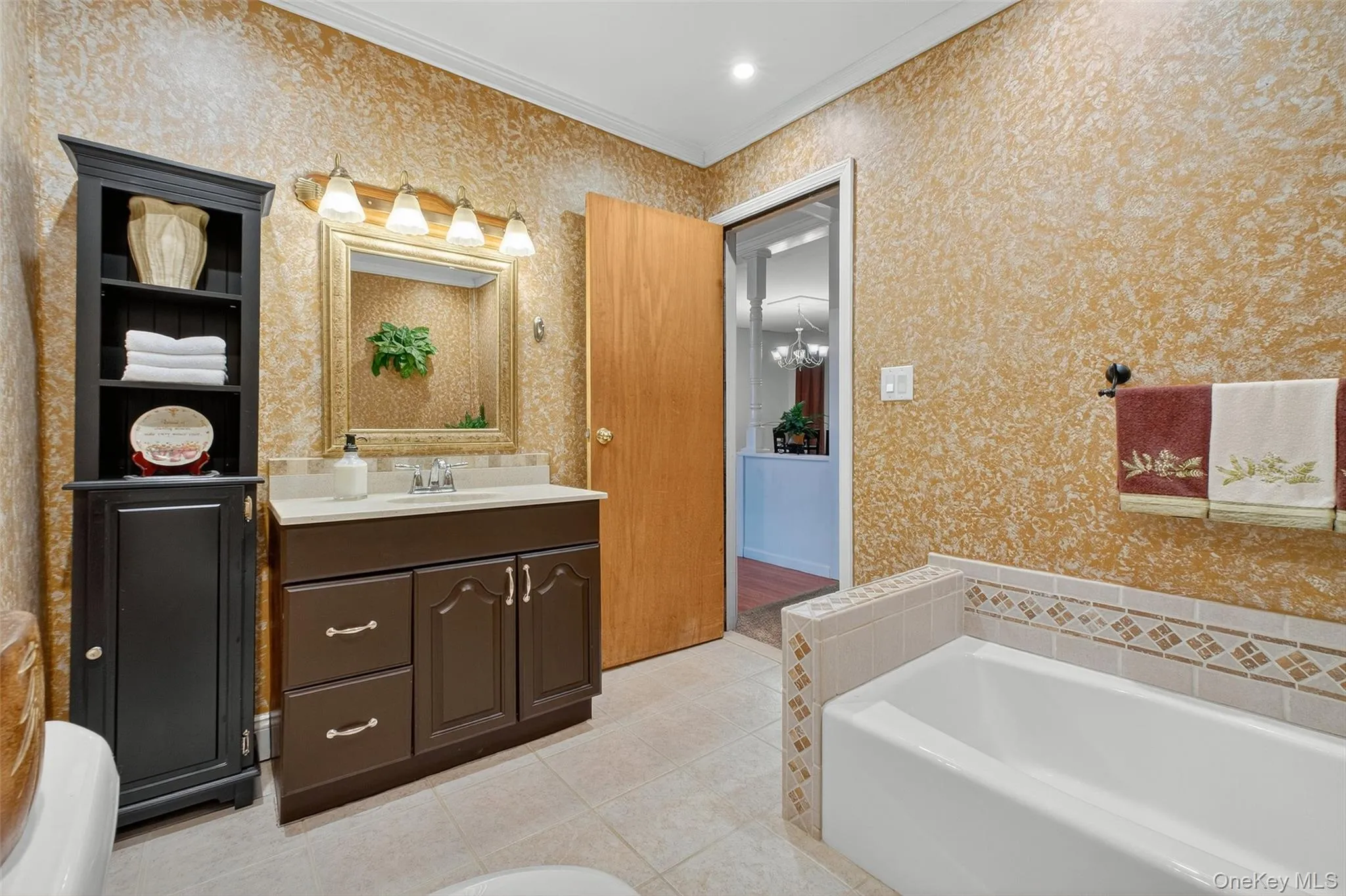 Full bathroom with a garden tub, vanity, crown molding, light tile patterned floors, and wallpapered walls Full bathroom with a garden tub, vanity, crown molding, light tile patterned floors, and wallpapered walls