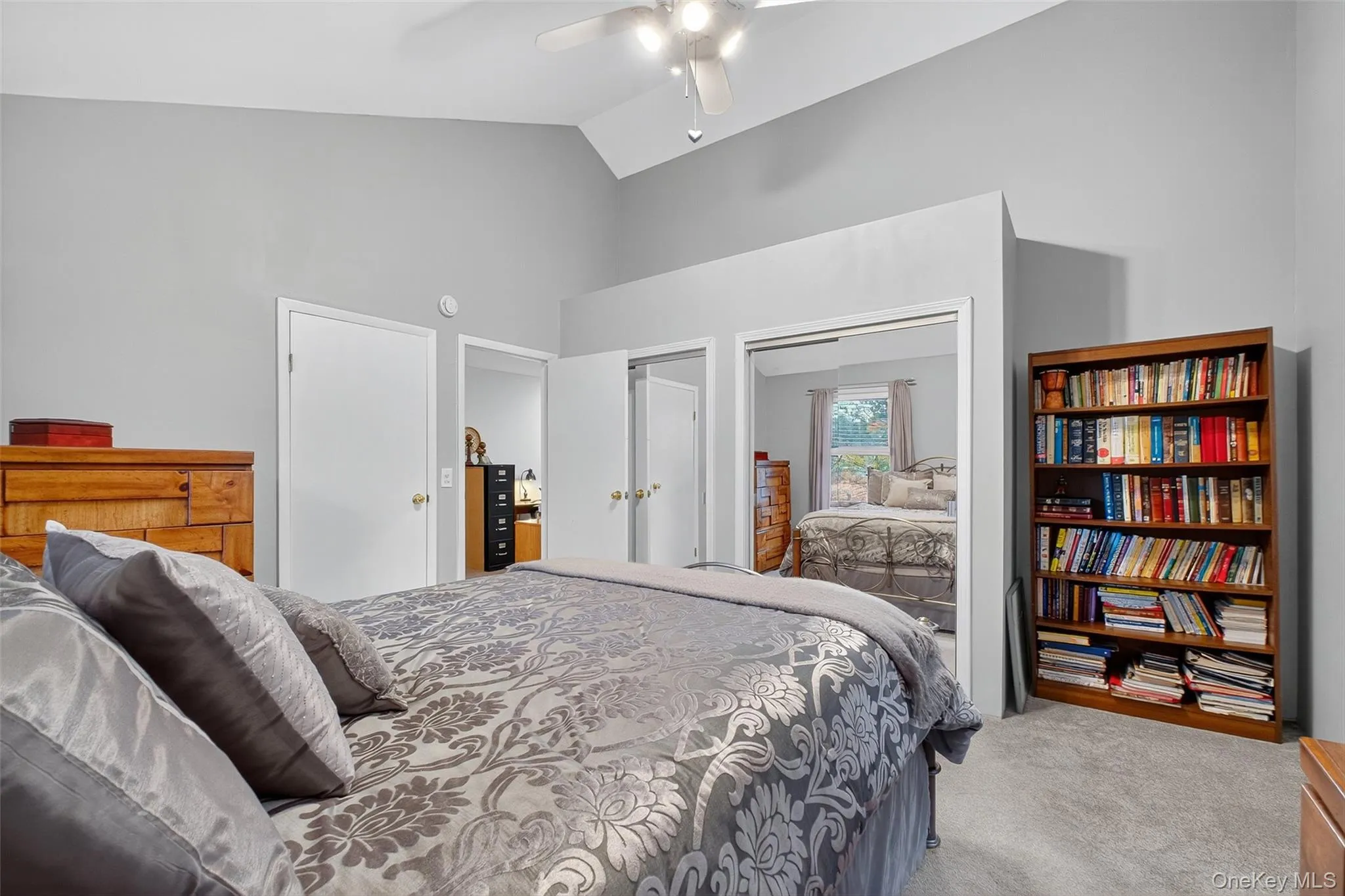 Bedroom featuring vaulted ceiling, carpet floors, multiple closets, and a ceiling fan Bedroom featuring vaulted ceiling, carpet floors, multiple closets, and a ceiling fan