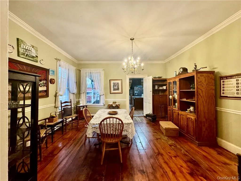 Dining space with crown molding, a notable chandelier, and dark hardwood / wood-style flooring Dining space with crown molding, a notable chandelier, and dark hardwood / wood-style flooring