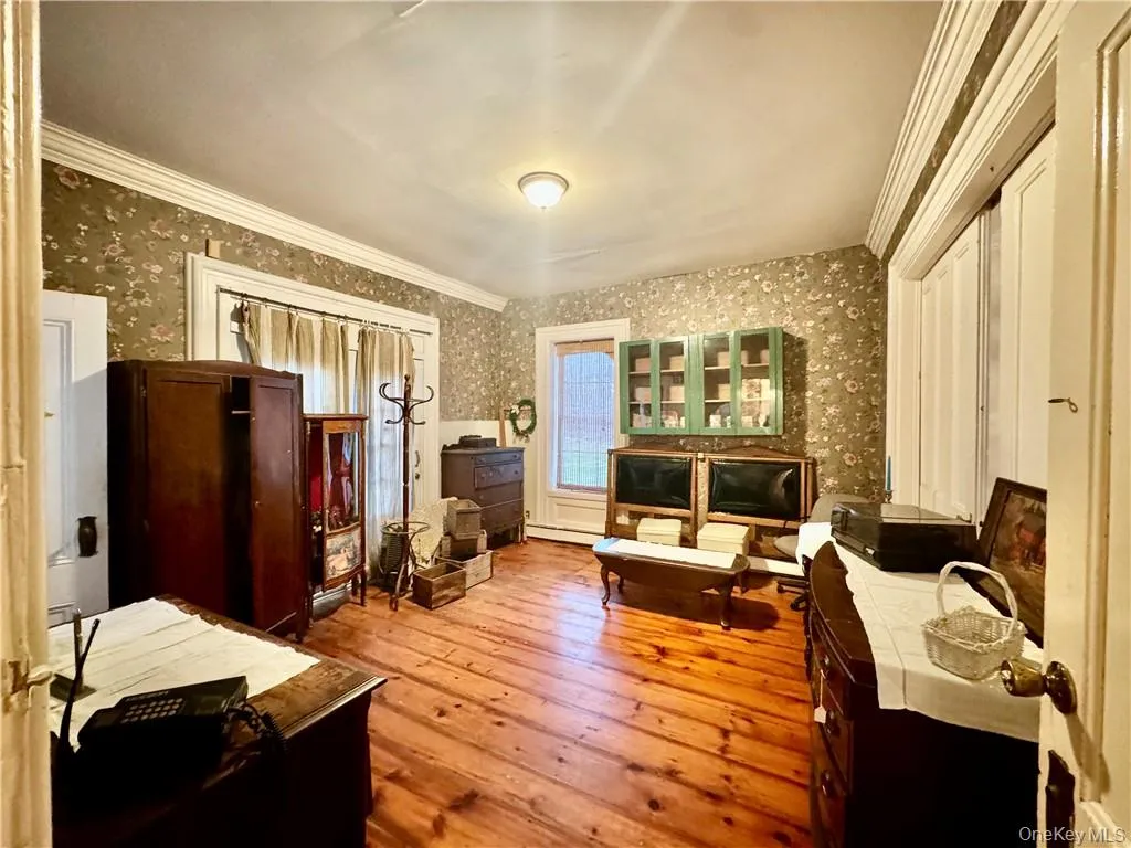 1st Floor bedroom featuring light hardwood / wood-style flooring, ornamental molding, and baseboard heating 1st Floor bedroom featuring light hardwood / wood-style flooring, ornamental molding, and baseboard heating