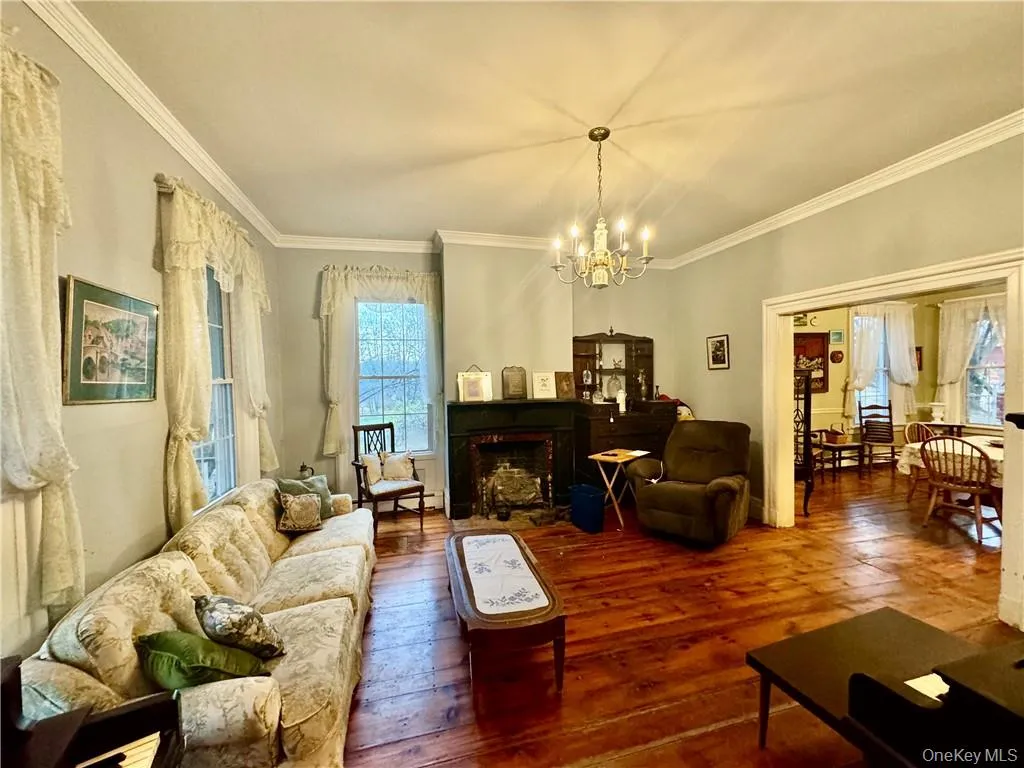 Living room with ornamental molding, a chandelier, and wood-type flooring Living room with ornamental molding, a chandelier, and wood-type flooring