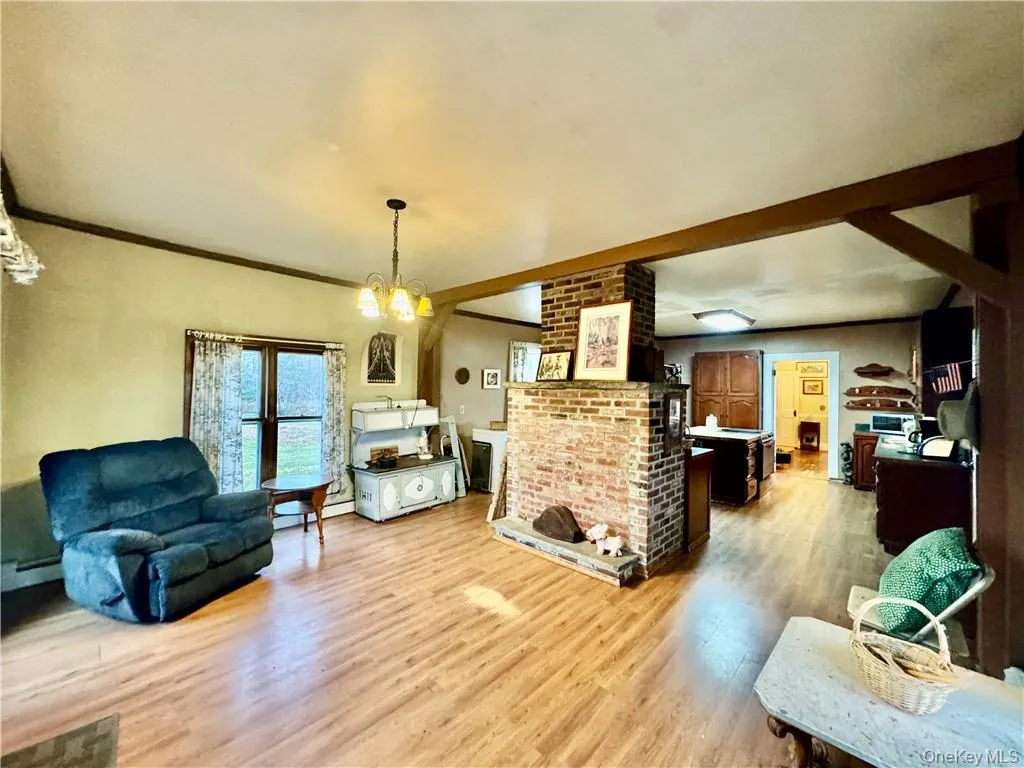 Siting room featuring light hardwood / wood-style flooring, ornamental molding, a notable chandelier, and a baseboard heating unit Siting room featuring light hardwood / wood-style flooring, ornamental molding, a notable chandelier, and a baseboard heating unit