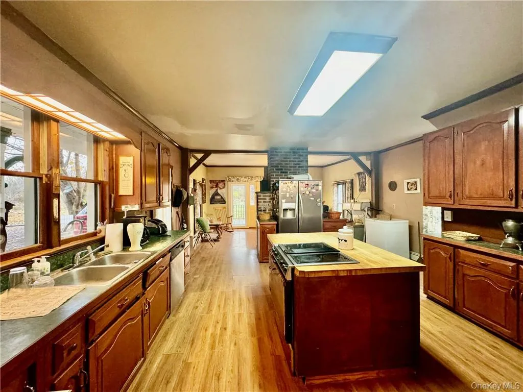 Kitchen featuring stainless steel appliances, sink, a center island, light wood-type flooring, and a skylight Kitchen featuring stainless steel appliances, sink, a center island, light wood-type flooring, and a skylight