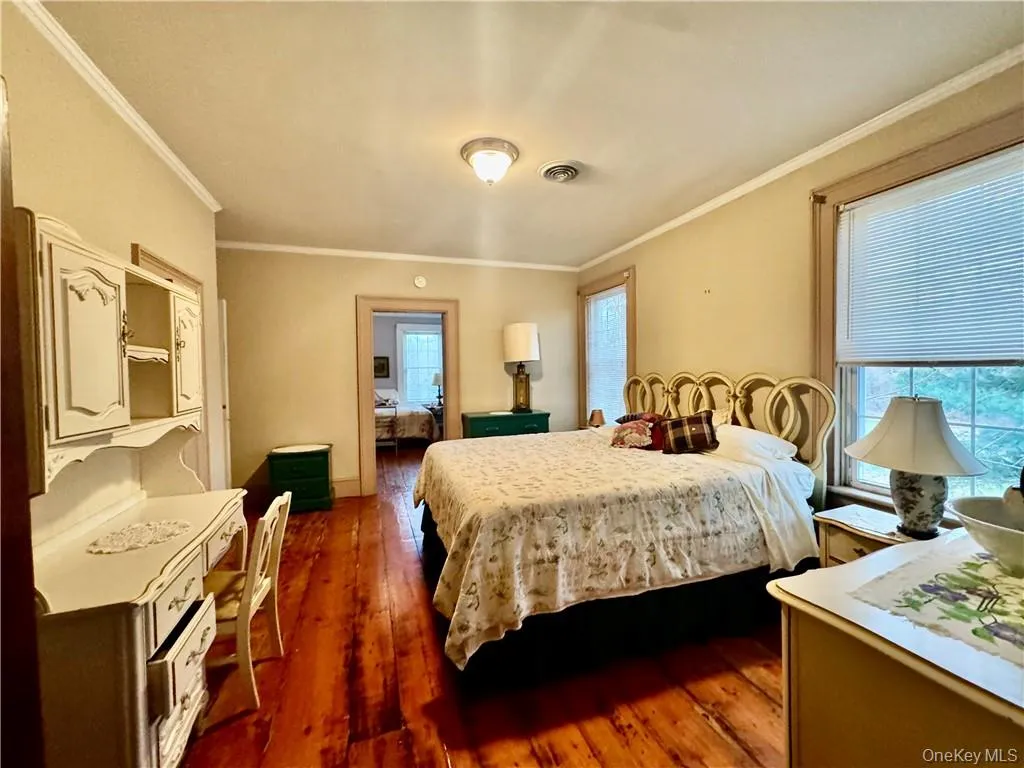 Bedroom with ornamental molding and dark wood-type flooring Bedroom with ornamental molding and dark wood-type flooring