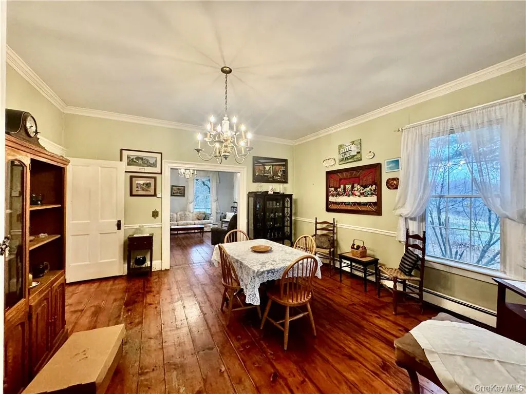 Dining room with ornamental molding, a chandelier, and dark hardwood / wood-style flooring Dining room with ornamental molding, a chandelier, and dark hardwood / wood-style flooring