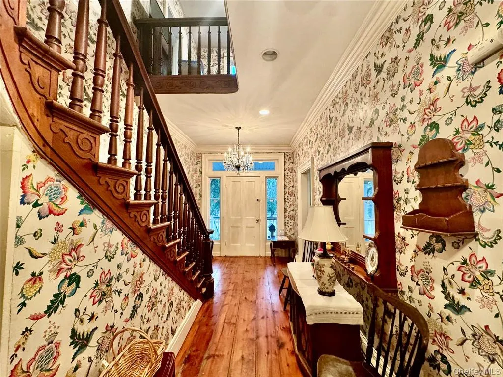 Foyer entrance featuring crown molding, a notable chandelier, and hardwood / wood-style floors Foyer entrance featuring crown molding, a notable chandelier, and hardwood / wood-style floors