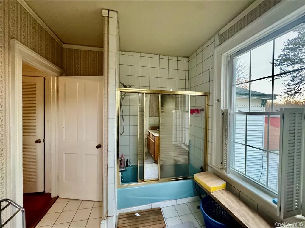 Bathroom with tile patterned floors, combined bath / shower with glass door, and ornamental molding Bathroom with tile patterned floors, combined bath / shower with glass door, and ornamental molding