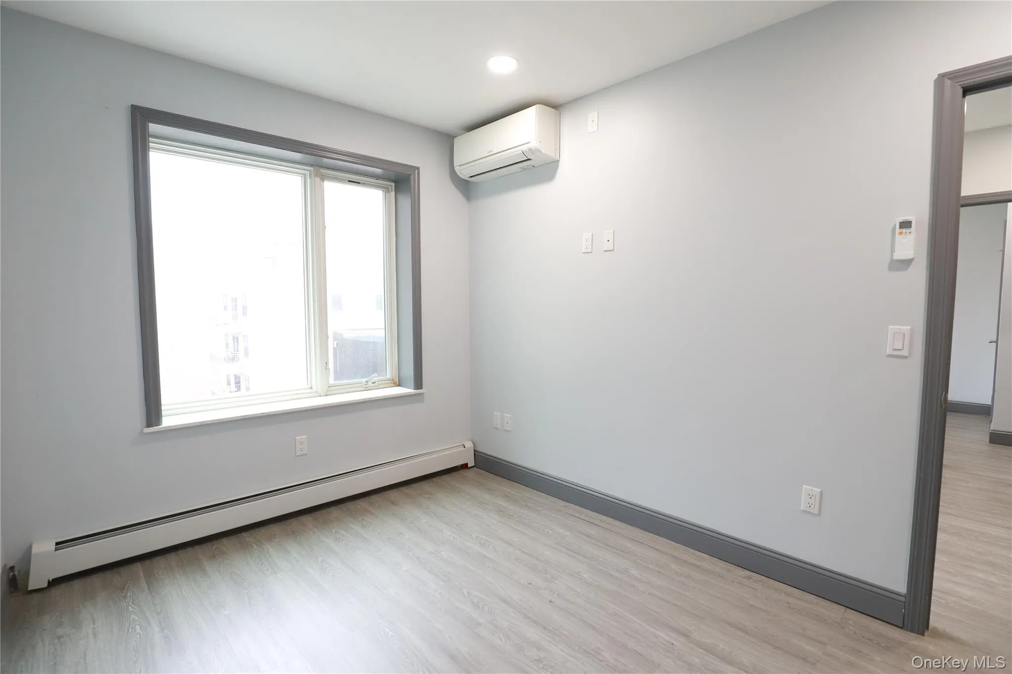 Room with a baseboard heating unit, light wood-style flooring, and recessed lighting Room with a baseboard heating unit, light wood-style flooring, and recessed lighting