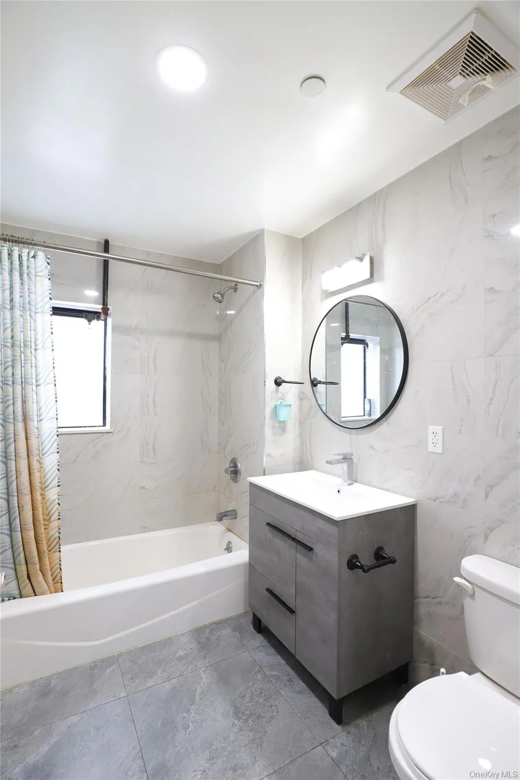 Bathroom featuring tile walls, vanity, and shower / tub combo with curtain Bathroom featuring tile walls, vanity, and shower / tub combo with curtain