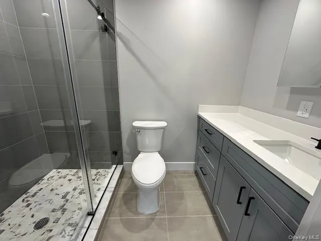Full bath featuring vanity, a shower stall, and light tile patterned floors Full bath featuring vanity, a shower stall, and light tile patterned floors
