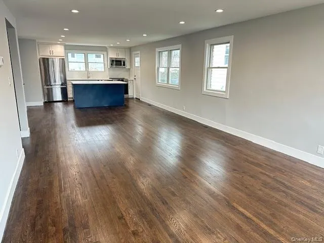 Kitchen and living room with recessed lighting and dark wood-style flooring Kitchen and living room with recessed lighting and dark wood-style flooring