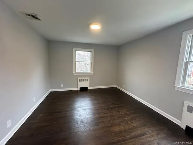 Bedroom featuring dark wood-style floors and radiator heating unit Bedroom featuring dark wood-style floors and radiator heating unit