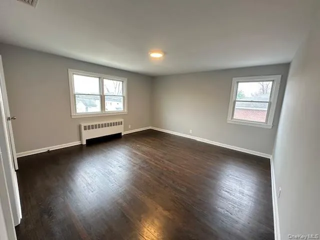 Bedroom with radiator and dark wood-type flooring Bedroom with radiator and dark wood-type flooring