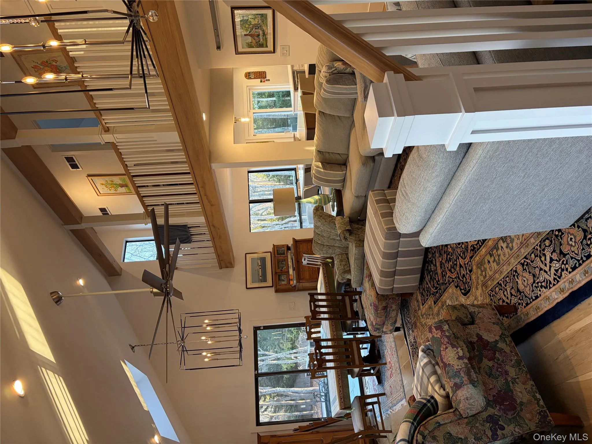 Living area with a chandelier, light wood finished floors, a skylight, ceiling fan, and vaulted ceiling Living area with a chandelier, light wood finished floors, a skylight, ceiling fan, and vaulted ceiling