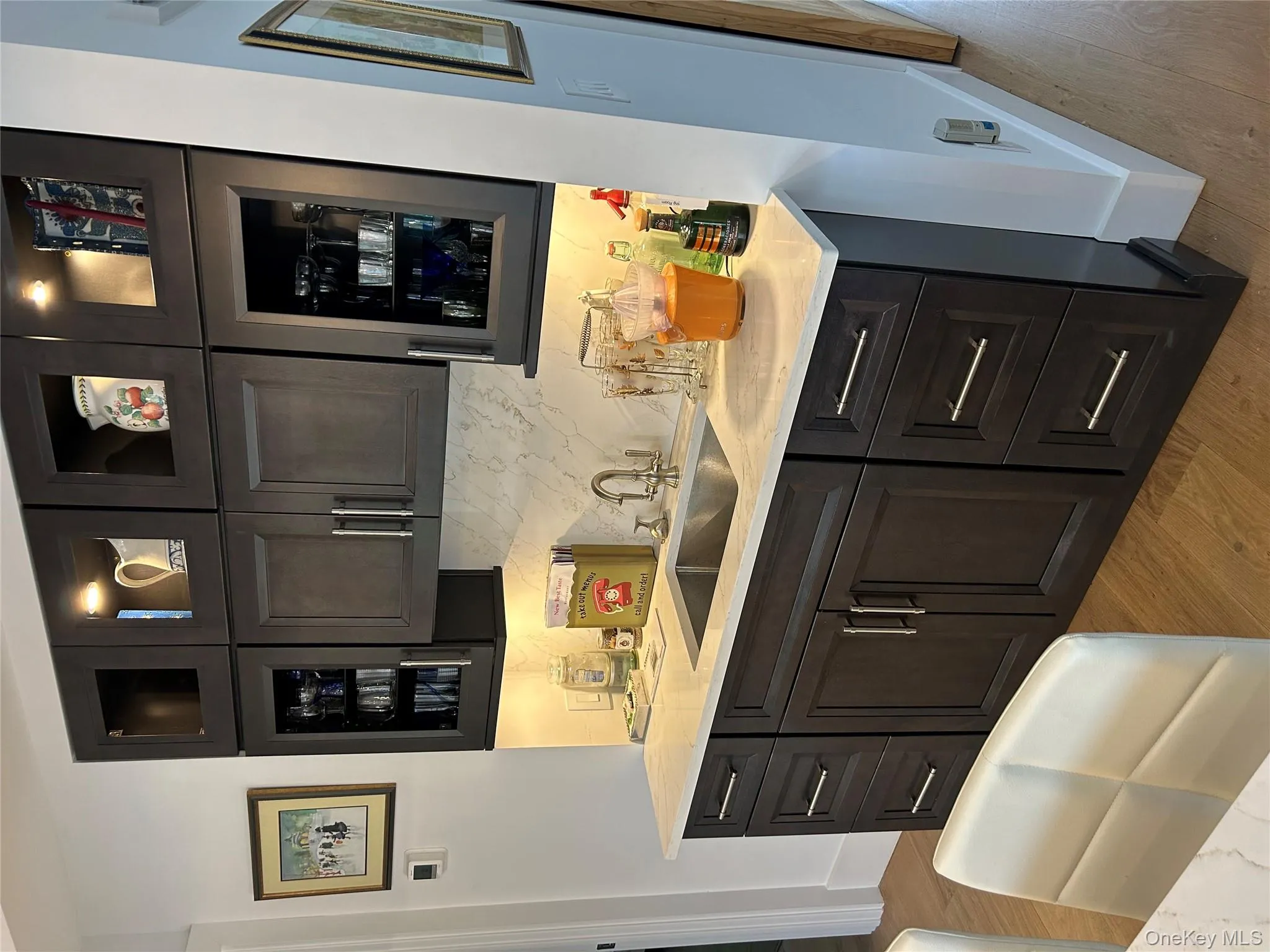 Bar with glass fronted cabinets, light stone countertops, light wood-style floors, and decorative backsplash Bar with glass fronted cabinets, light stone countertops, light wood-style floors, and decorative backsplash