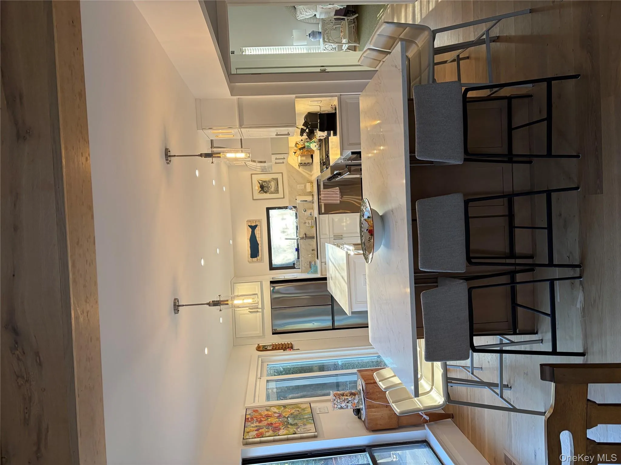 Kitchen with a center island, white cabinets, dark wood-type flooring, and hanging light fixtures Kitchen with a center island, white cabinets, dark wood-type flooring, and hanging light fixtures