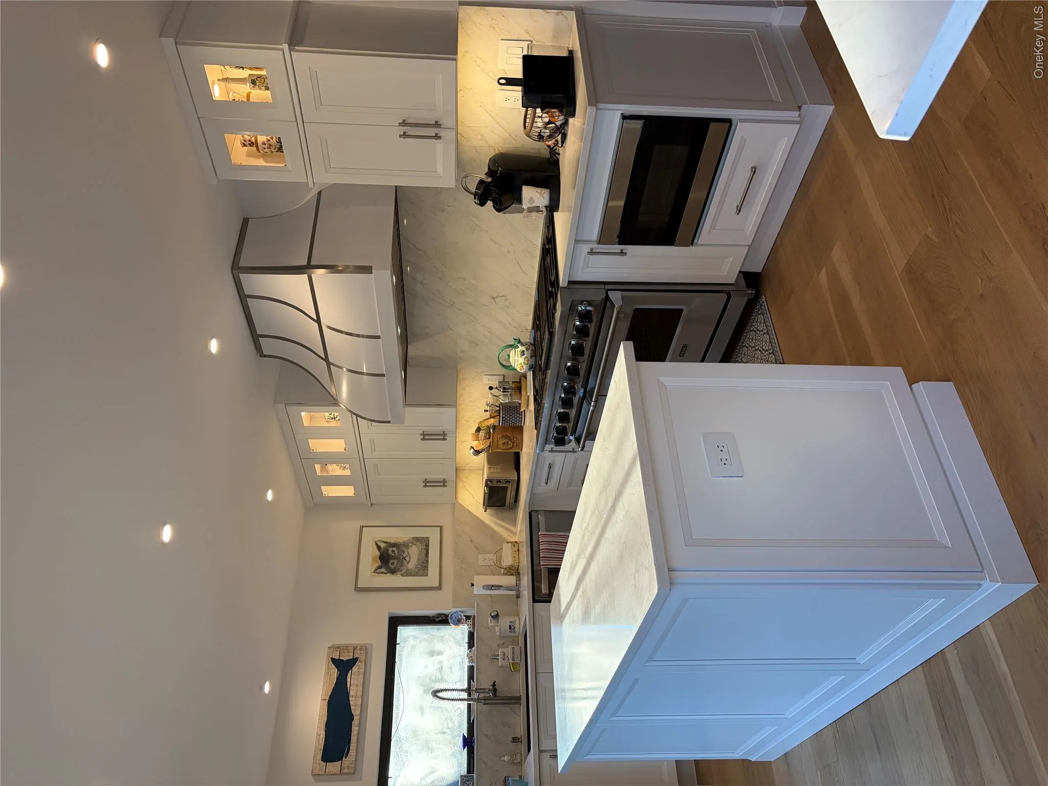 Kitchen with glass insert cabinets, stainless steel appliances, dark wood-type flooring, a center island, and white cabinetry Kitchen with glass insert cabinets, stainless steel appliances, dark wood-type flooring, a center island, and white cabinetry