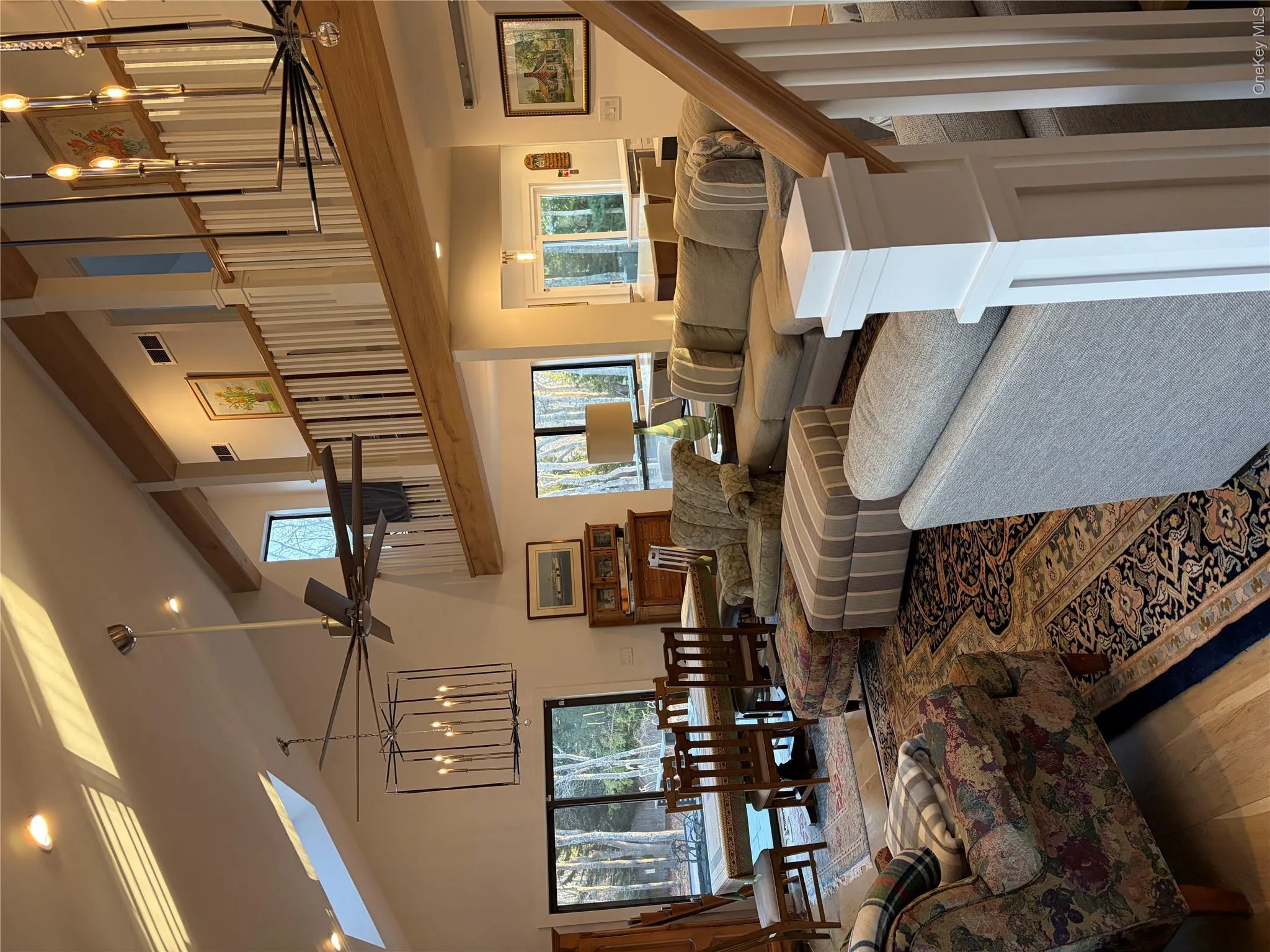 Living area with a chandelier, light wood finished floors, a skylight, ceiling fan, and vaulted ceiling Living area with a chandelier, light wood finished floors, a skylight, ceiling fan, and vaulted ceiling