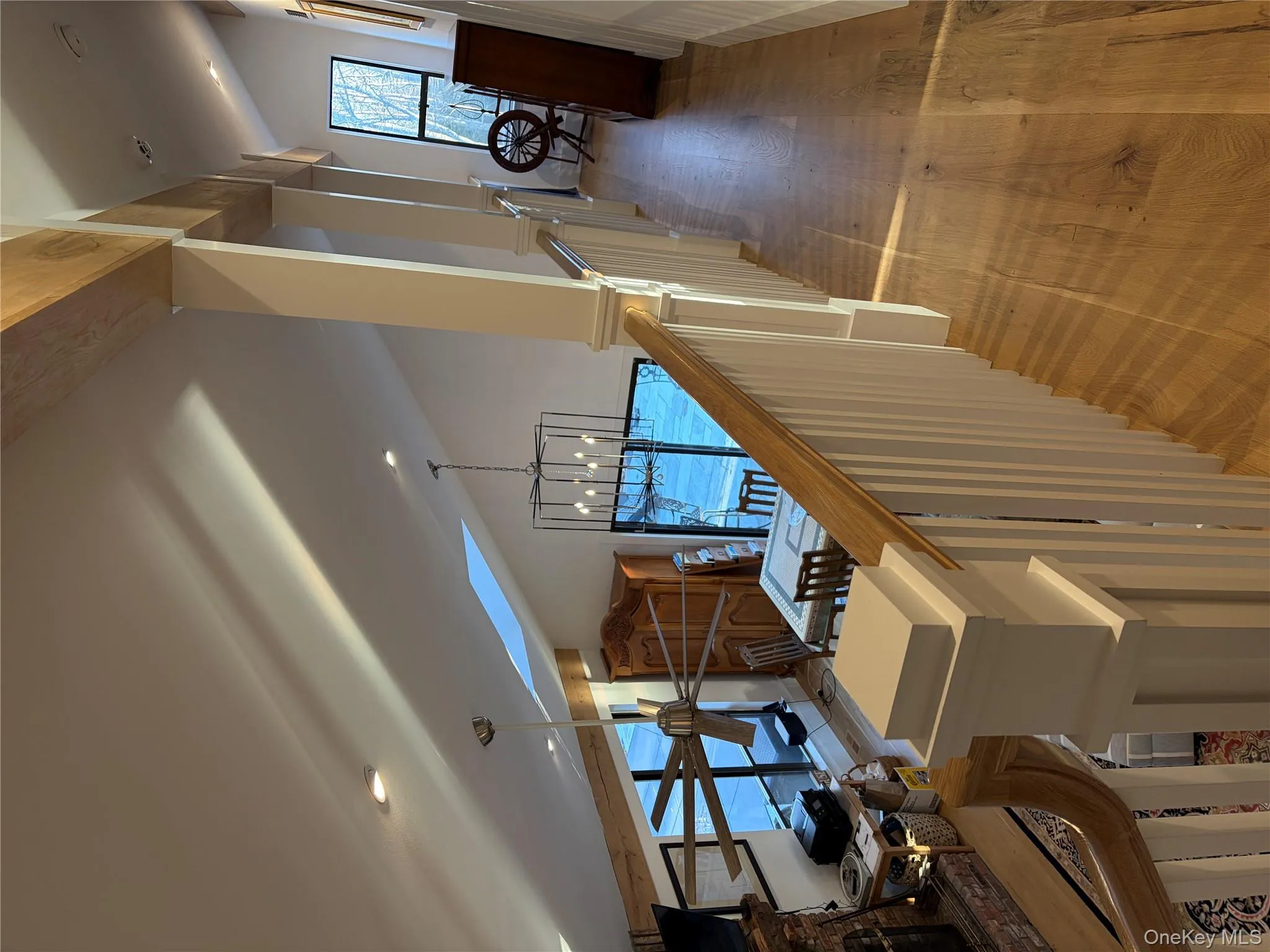 Corridor featuring healthy amount of natural light, lofted ceiling, a chandelier, and light wood-style flooring Corridor featuring healthy amount of natural light, lofted ceiling, a chandelier, and light wood-style flooring