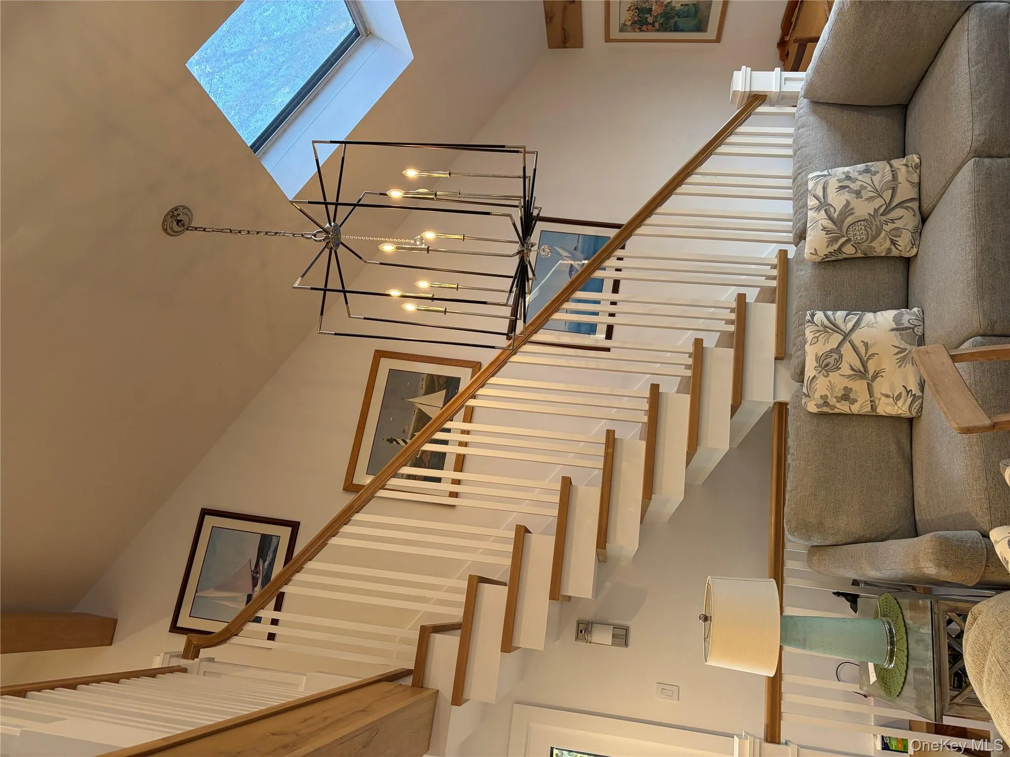 Living area featuring lofted ceiling, a skylight, and suspended lighting Living area featuring lofted ceiling, a skylight, and suspended lighting