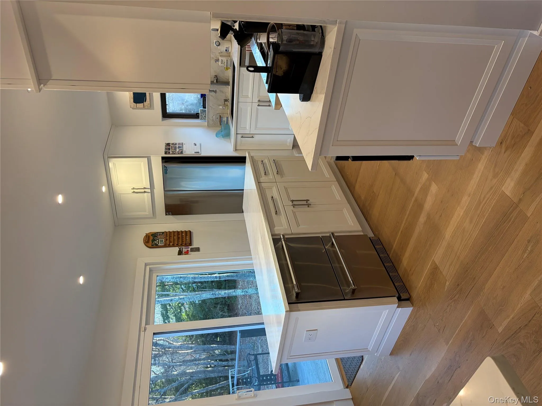 Kitchen with a kitchen island, white cabinets, light wood finished floors, recessed lighting, and stainless steel appliances Kitchen with a kitchen island, white cabinets, light wood finished floors, recessed lighting, and stainless steel appliances