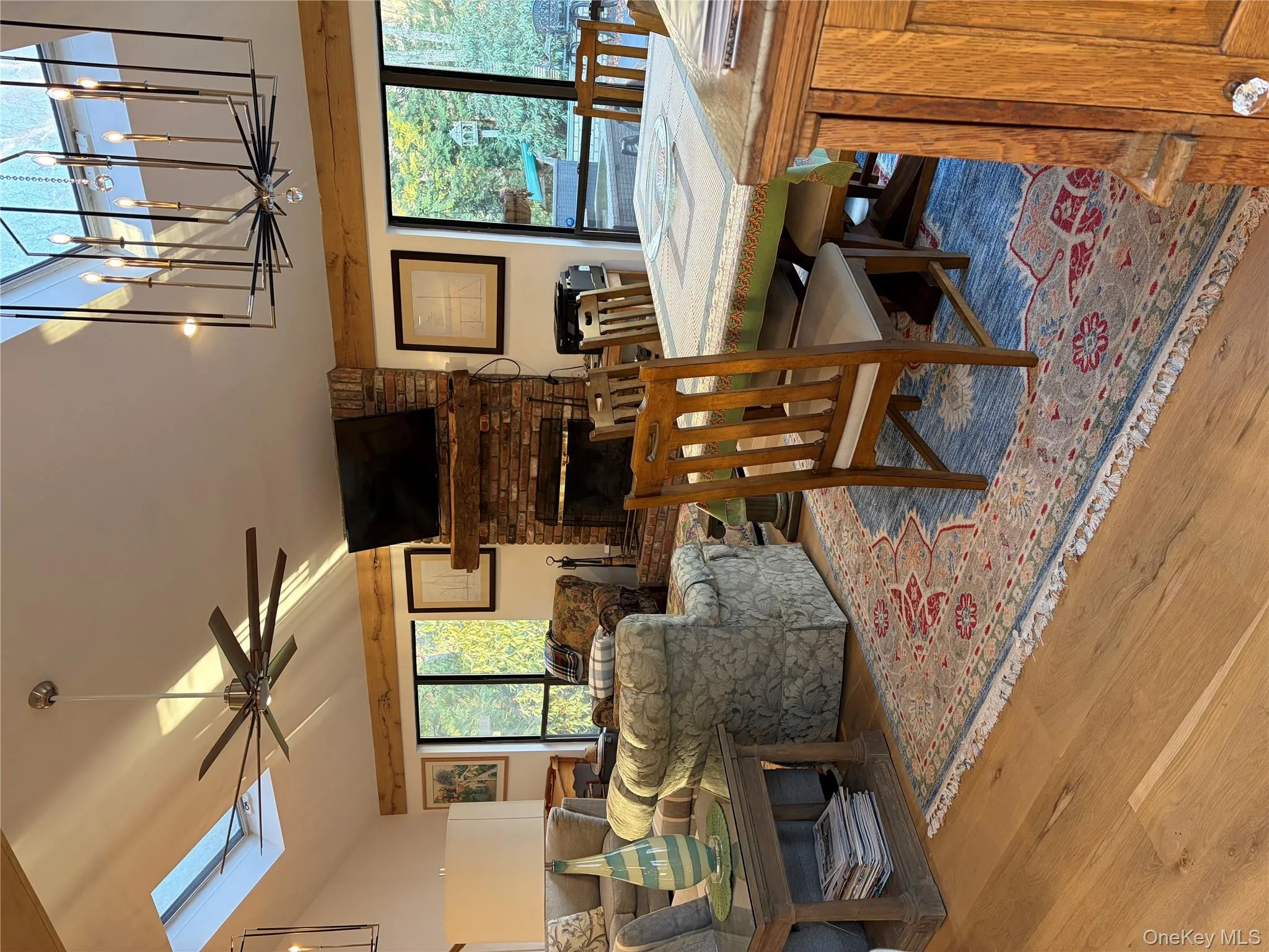 Dining area with a skylight, a ceiling fan, light wood-style flooring, suspended lighting, and a brick fireplace Dining area with a skylight, a ceiling fan, light wood-style flooring, suspended lighting, and a brick fireplace
