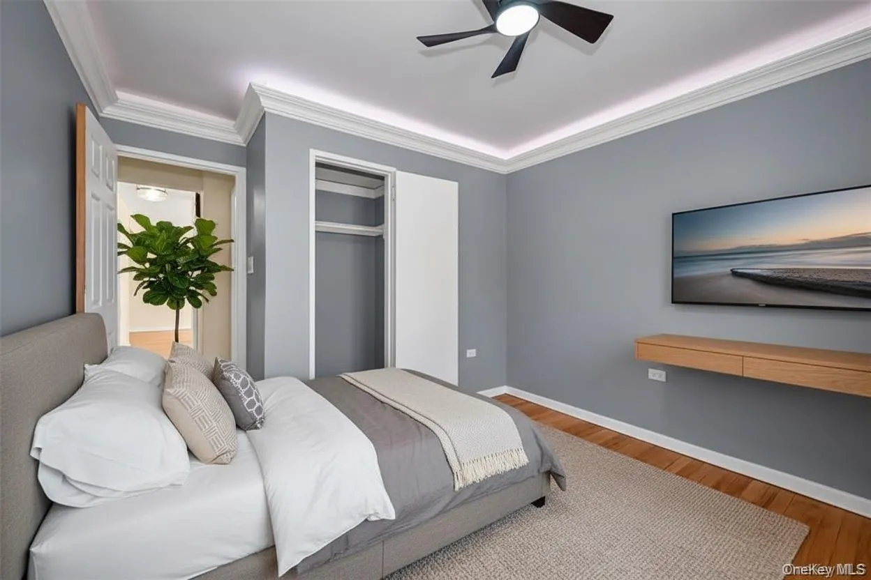 Bedroom with wood finished floors, crown molding, a closet, and ceiling fan. Digitally staged. Bedroom with wood finished floors, crown molding, a closet, and ceiling fan. Digitally staged.