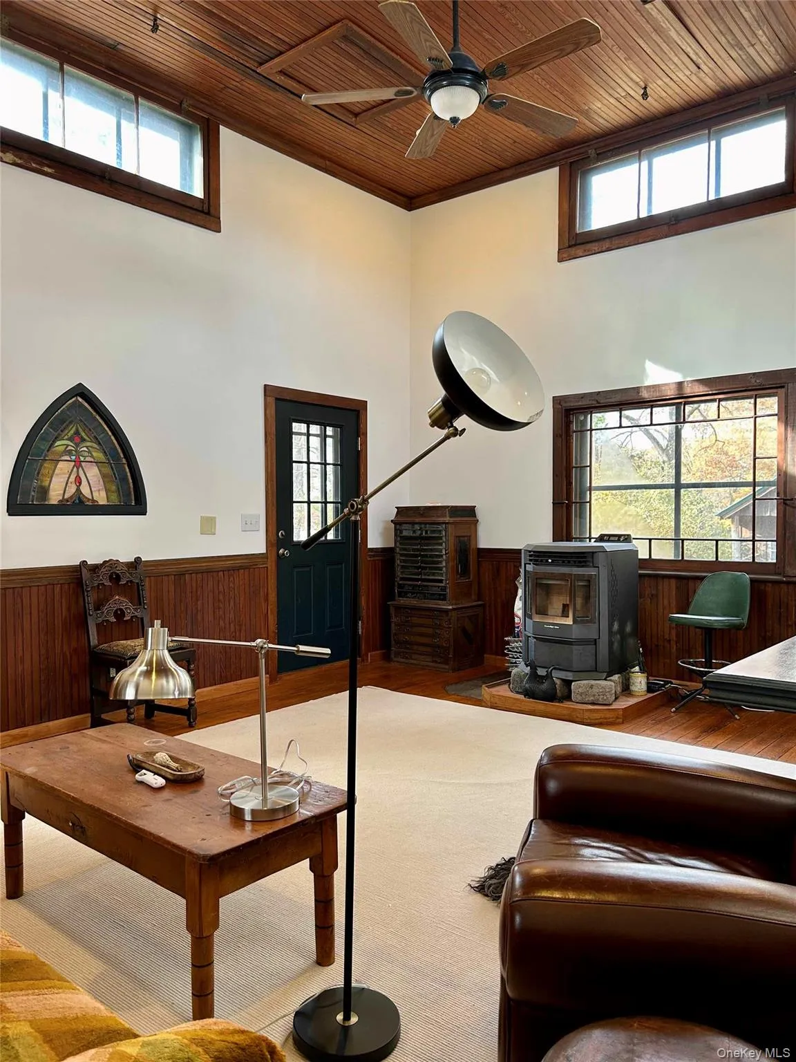 Living room featuring a pellet stove, ceiling fan, a high wooden ceiling Living room featuring a pellet stove, ceiling fan, a high wooden ceiling