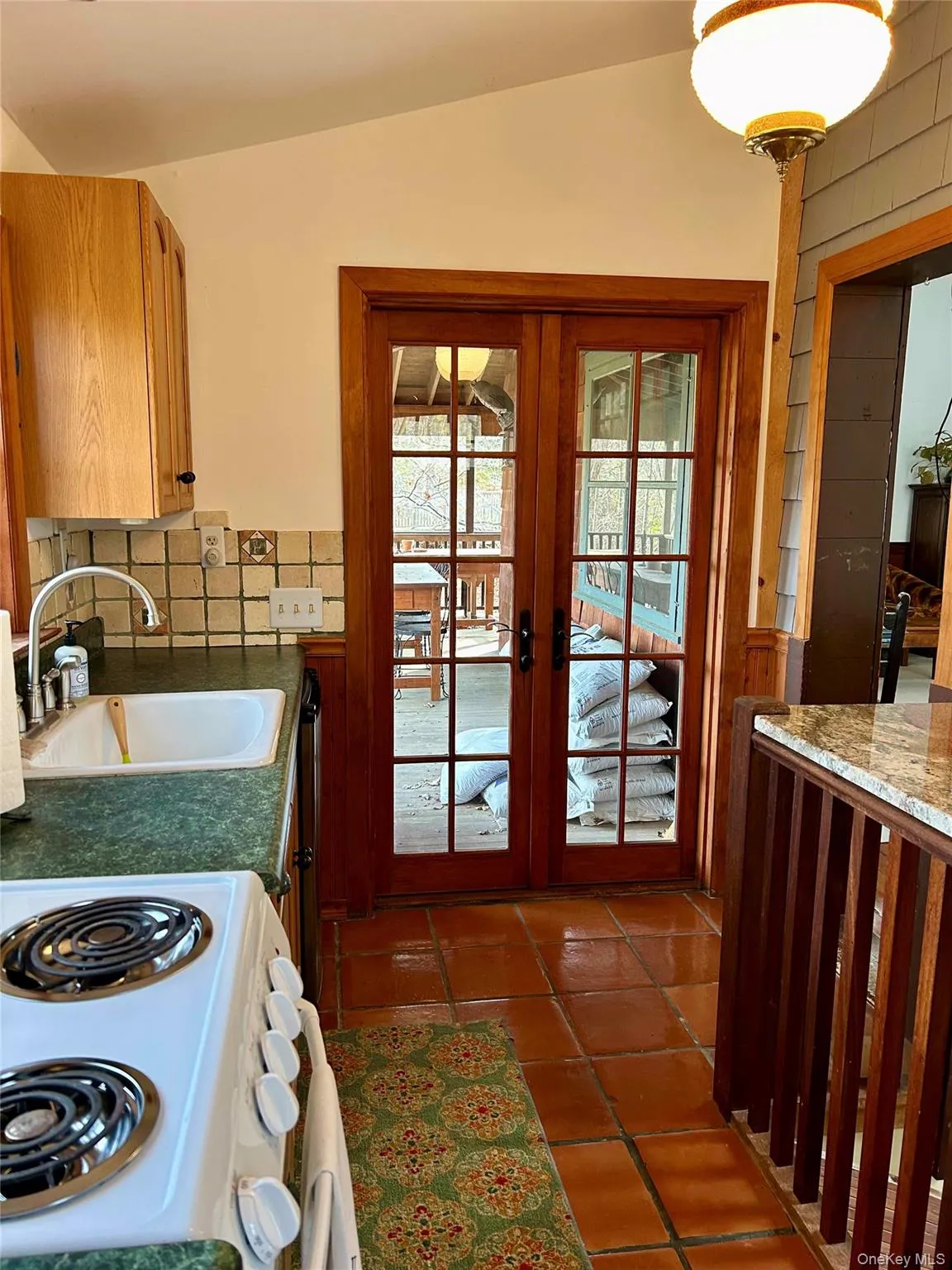 Kitchen with lofted ceiling, sink, terra cotta tile floor, and french doors Kitchen with lofted ceiling, sink, terra cotta tile floor, and french doors