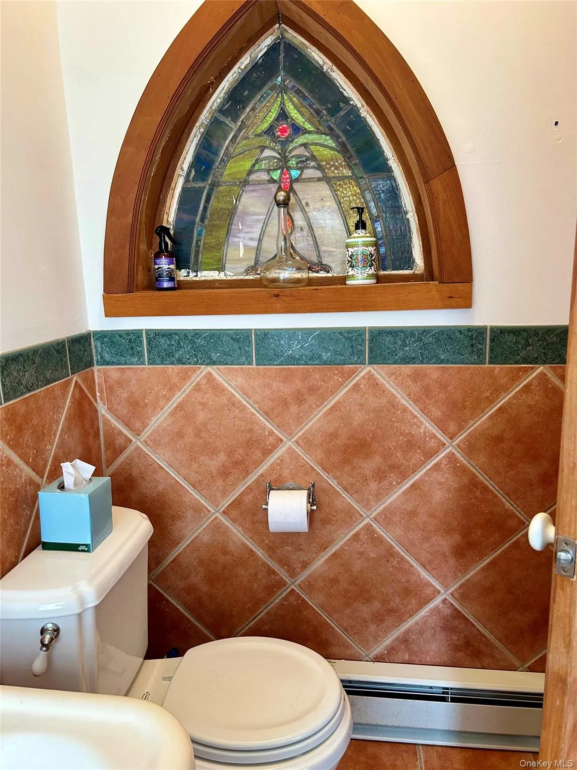 Bathroom with toilet, tile walls, and a baseboard heating unit Bathroom with toilet, tile walls, and a baseboard heating unit