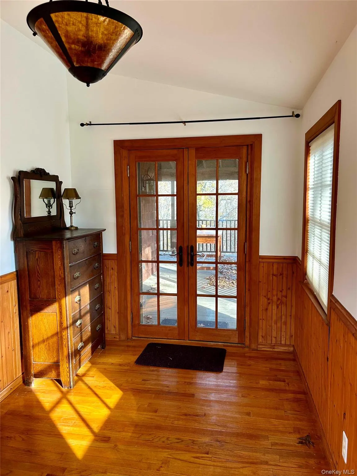 Bedroom featuring vaulted ceiling, wooden walls, and french doors Bedroom featuring vaulted ceiling, wooden walls, and french doors