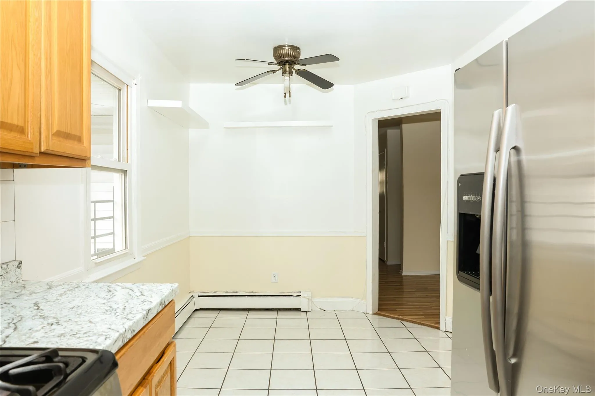 Kitchen featuring stainless steel fridge, gas stove, a ceiling fan, light countertops, and light tile patterned flooring Kitchen featuring stainless steel fridge, gas stove, a ceiling fan, light countertops, and light tile patterned flooring