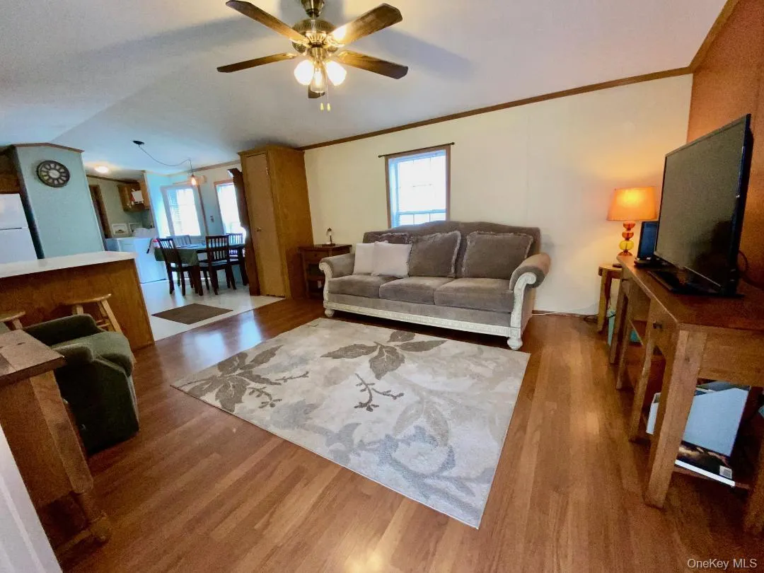 There's a spacious living room with wood like laminate floors, a vaulted ceilings, crown molding, and a ceiling light fan. There's a spacious living room with wood like laminate floors, a vaulted ceilings, crown molding, and a ceiling light fan.