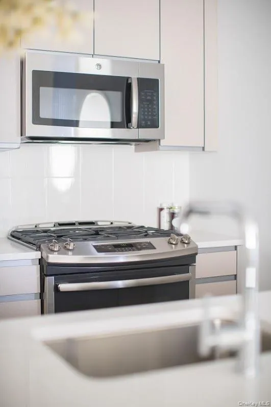 Kitchen view of appliances with stainless steel finishes, light countertops, and backsplash Kitchen view of appliances with stainless steel finishes, light countertops, and backsplash