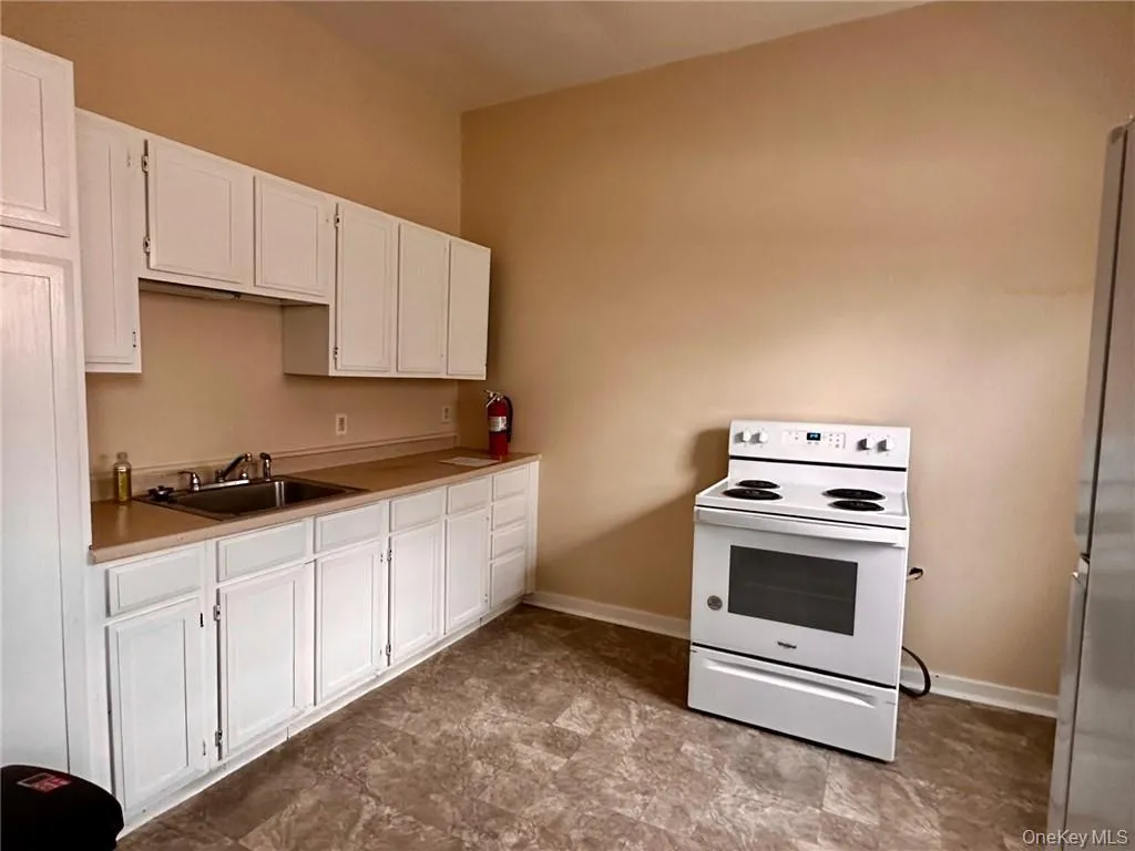 Kitchen with white cabinets, stainless steel fridge, sink, and electric range Kitchen with white cabinets, stainless steel fridge, sink, and electric range