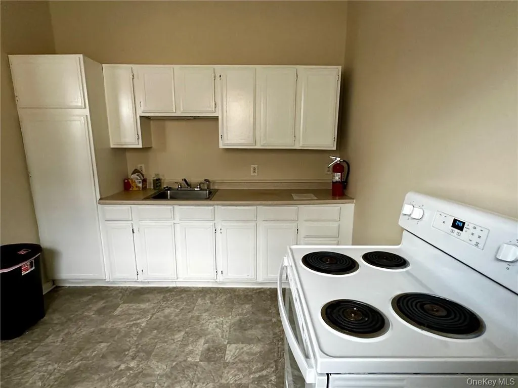 Kitchen featuring white cabinetry, white electric range, and sink Kitchen featuring white cabinetry, white electric range, and sink
