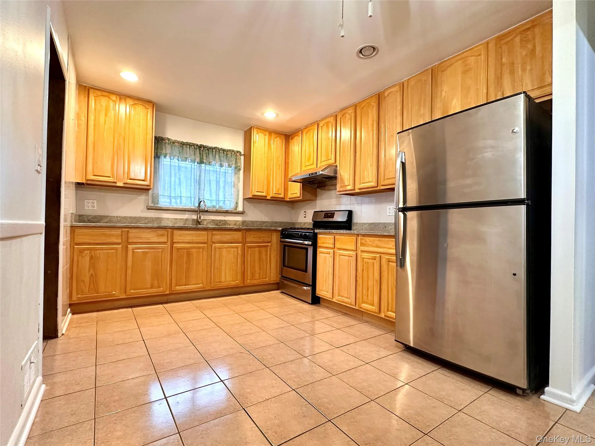 Kitchen featuring stainless steel appliances, recessed lighting, light tile patterned floors, light wood finish cabinets, and Granite countertops Kitchen featuring stainless steel appliances, recessed lighting, light tile patterned floors, light wood finish cabinets, and Granite countertops