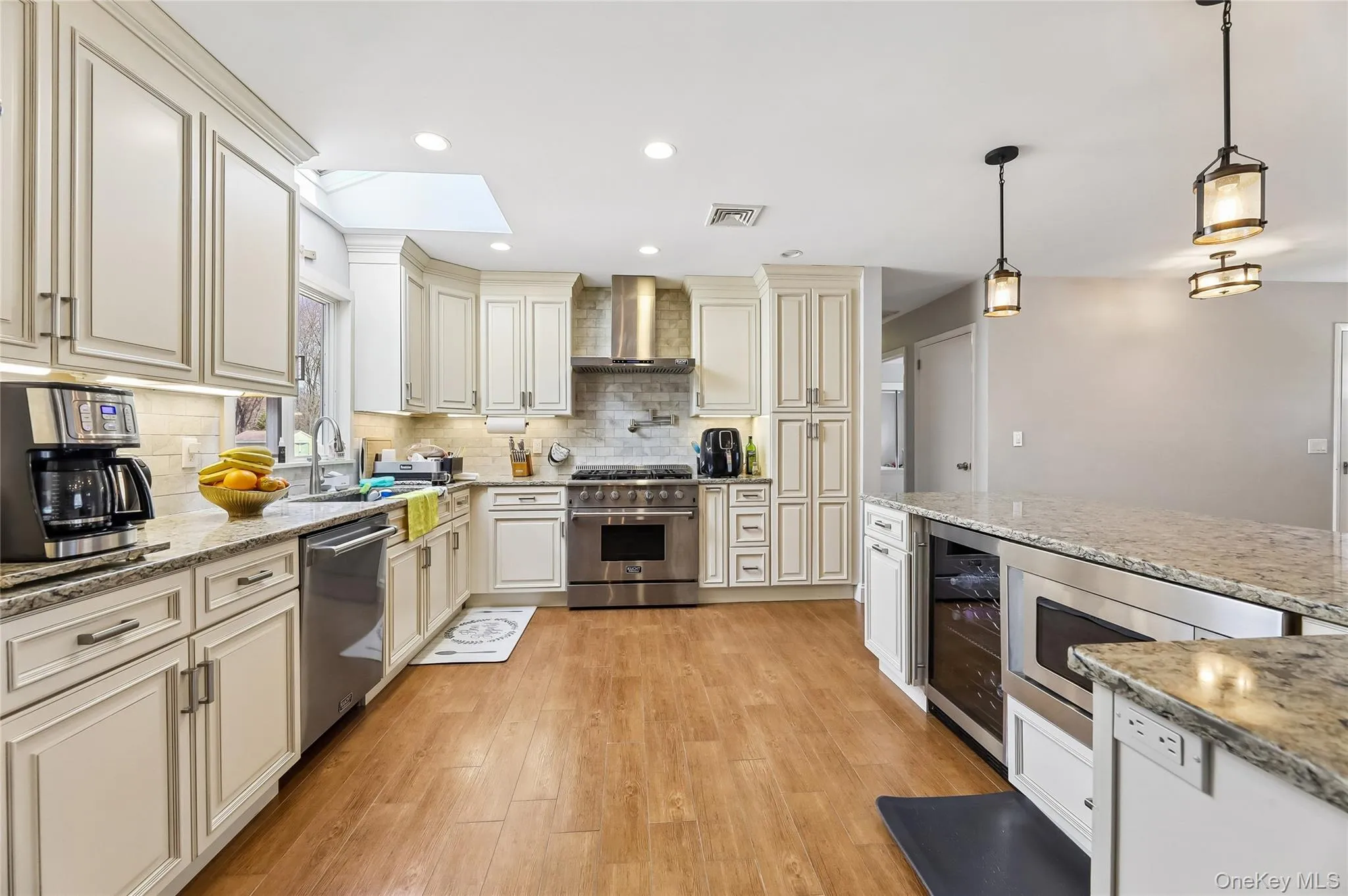 Gourmet kitchen featuring light wood-finish flooring, white cabinetry, granite countertops, and stainless steel appliances. Gourmet kitchen featuring light wood-finish flooring, white cabinetry, granite countertops, and stainless steel appliances.