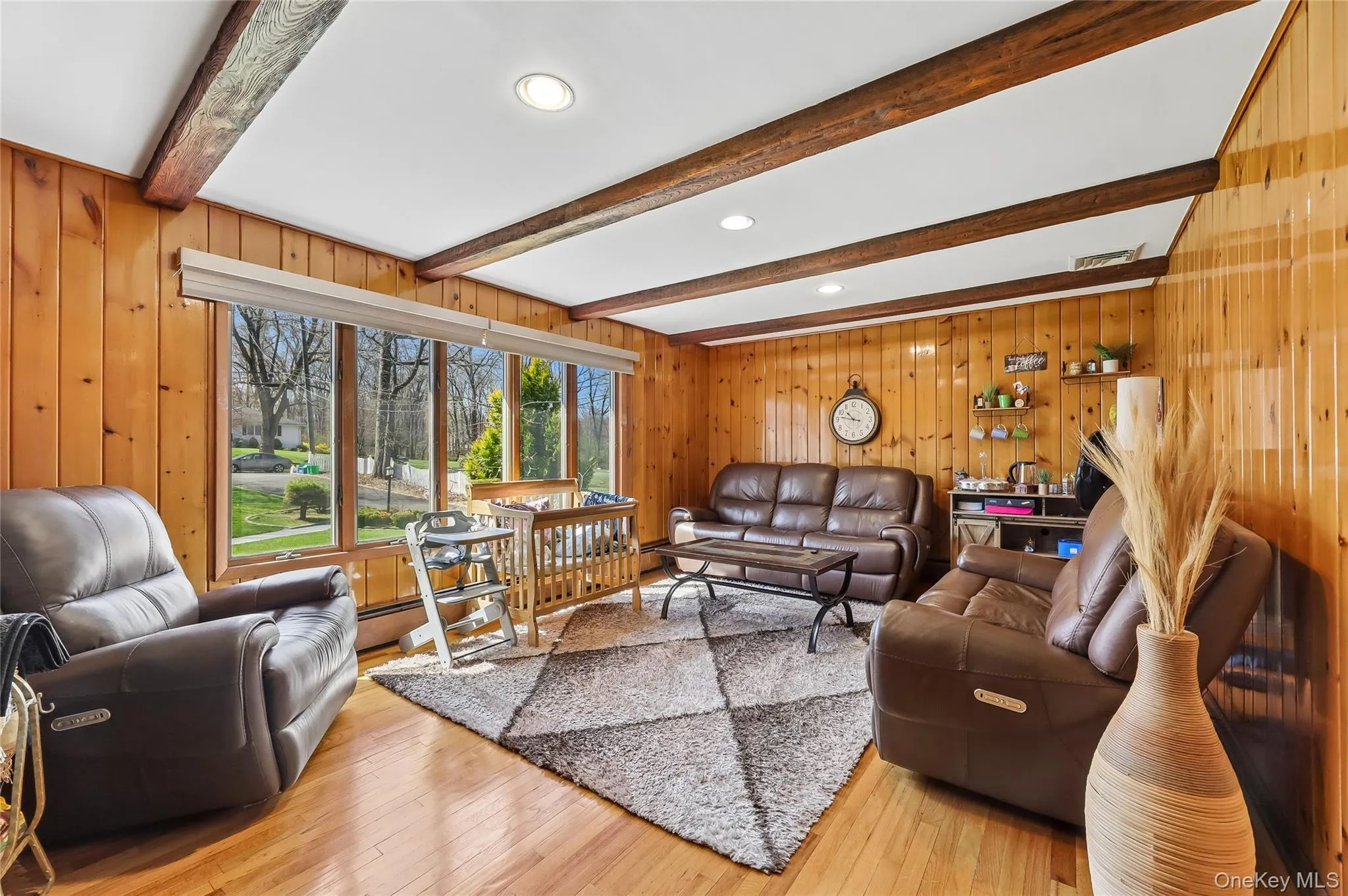 Living area featuring wood-finish flooring, wood paneling, and exposed ceiling beams Living area featuring wood-finish flooring, wood paneling, and exposed ceiling beams
