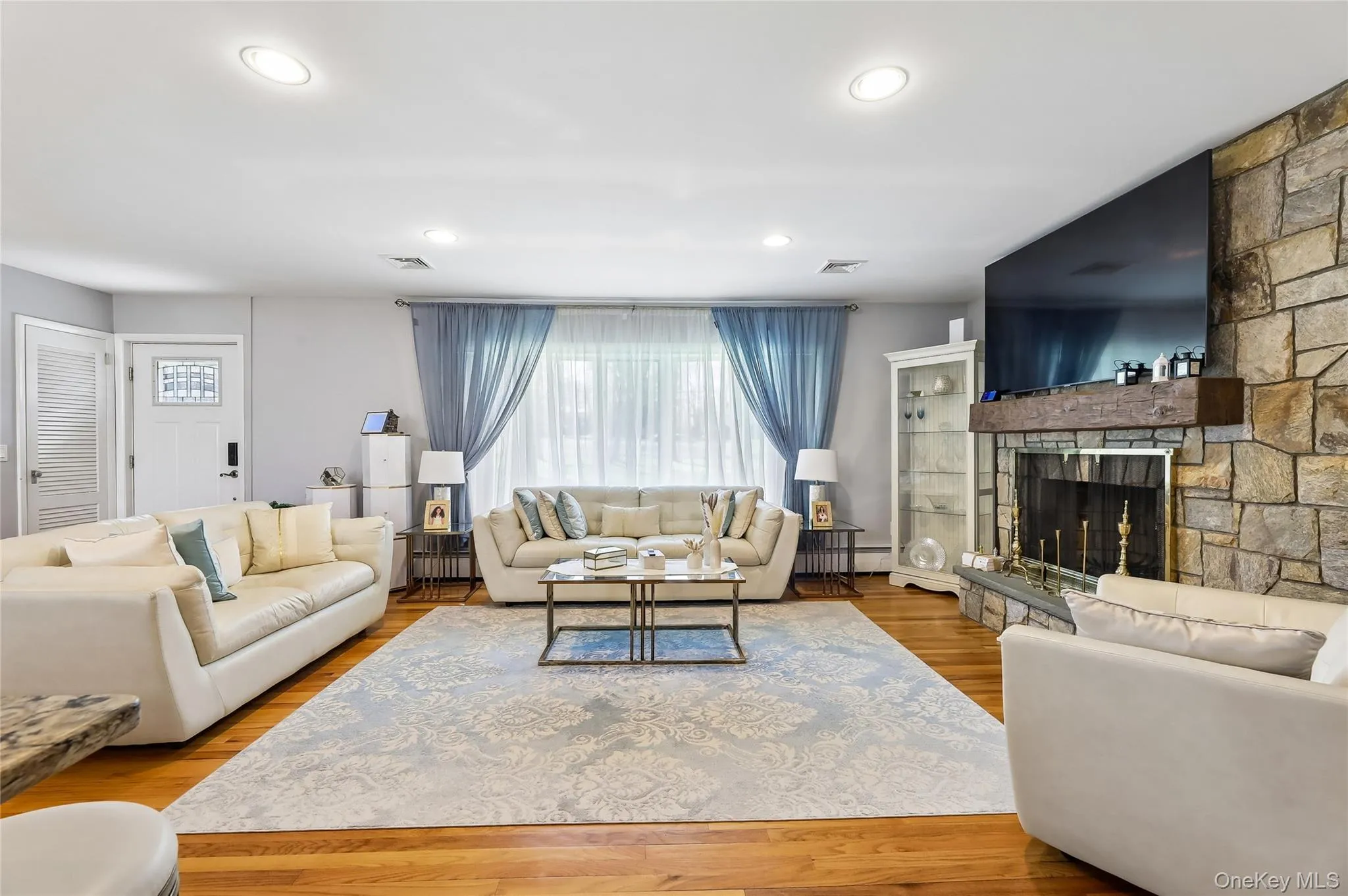 Spacious living room featuring hardwood flooring, and stone fireplace . Spacious living room featuring hardwood flooring, and stone fireplace .