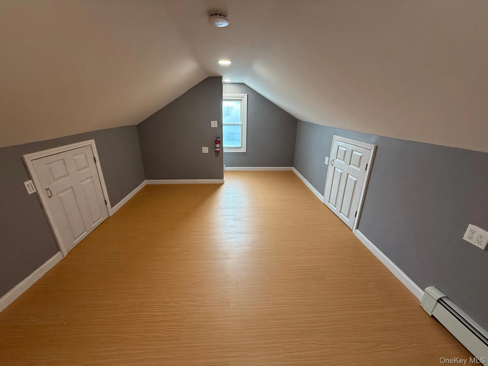 Additional living space featuring baseboard heating and wood finished floors Additional living space featuring baseboard heating and wood finished floors