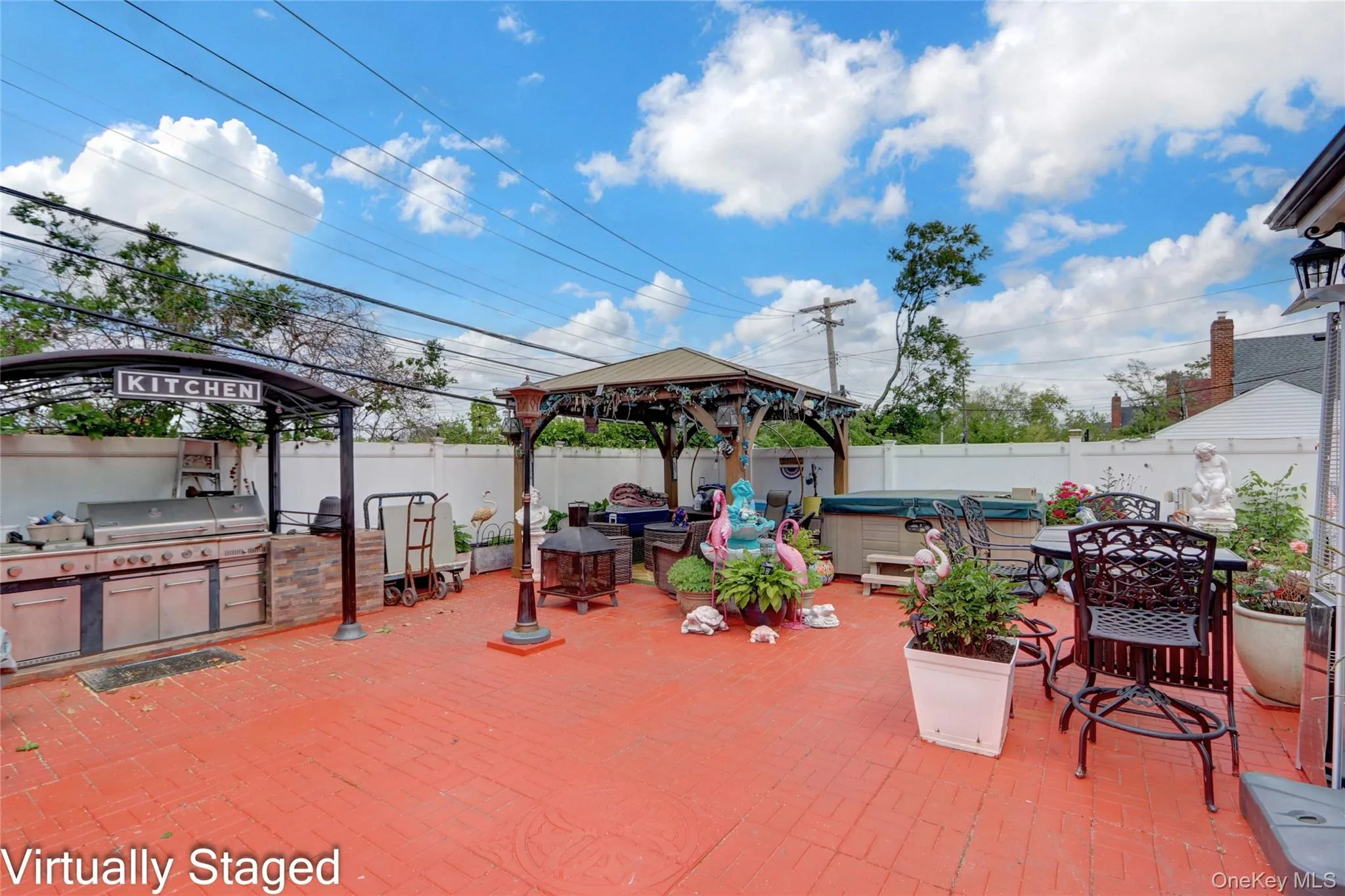 Fenced backyard featuring an outdoor kitchen / dining area, a patio, a hot tub, and a gazebo Fenced backyard featuring an outdoor kitchen / dining area, a patio, a hot tub, and a gazebo