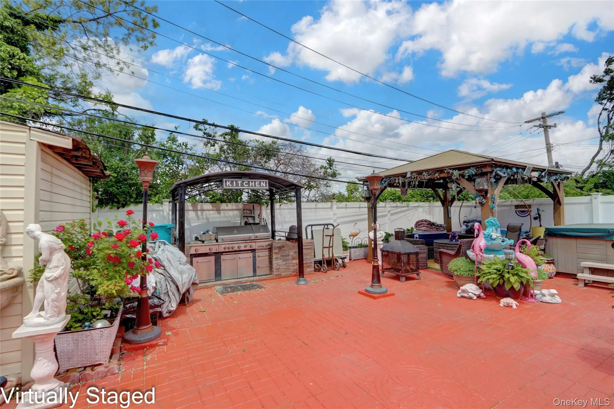 Fenced backyard featuring a gazebo, a hot tub, a patio area, and an outdoor kitchen Fenced backyard featuring a gazebo, a hot tub, a patio area, and an outdoor kitchen