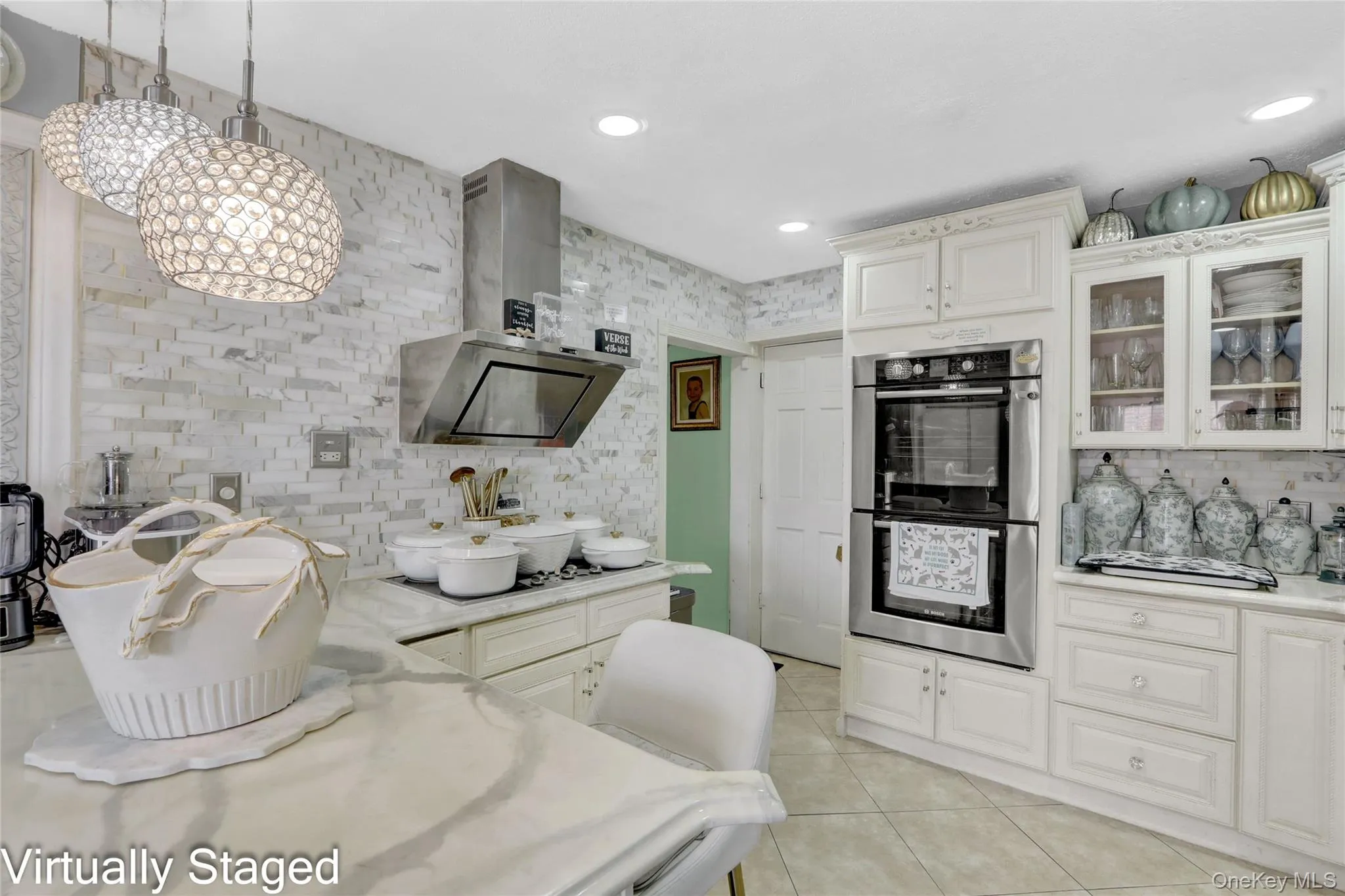 Kitchen with stainless steel double oven, glass insert cabinets, white cabinetry, light tile patterned floors, and light stone counters Kitchen with stainless steel double oven, glass insert cabinets, white cabinetry, light tile patterned floors, and light stone counters