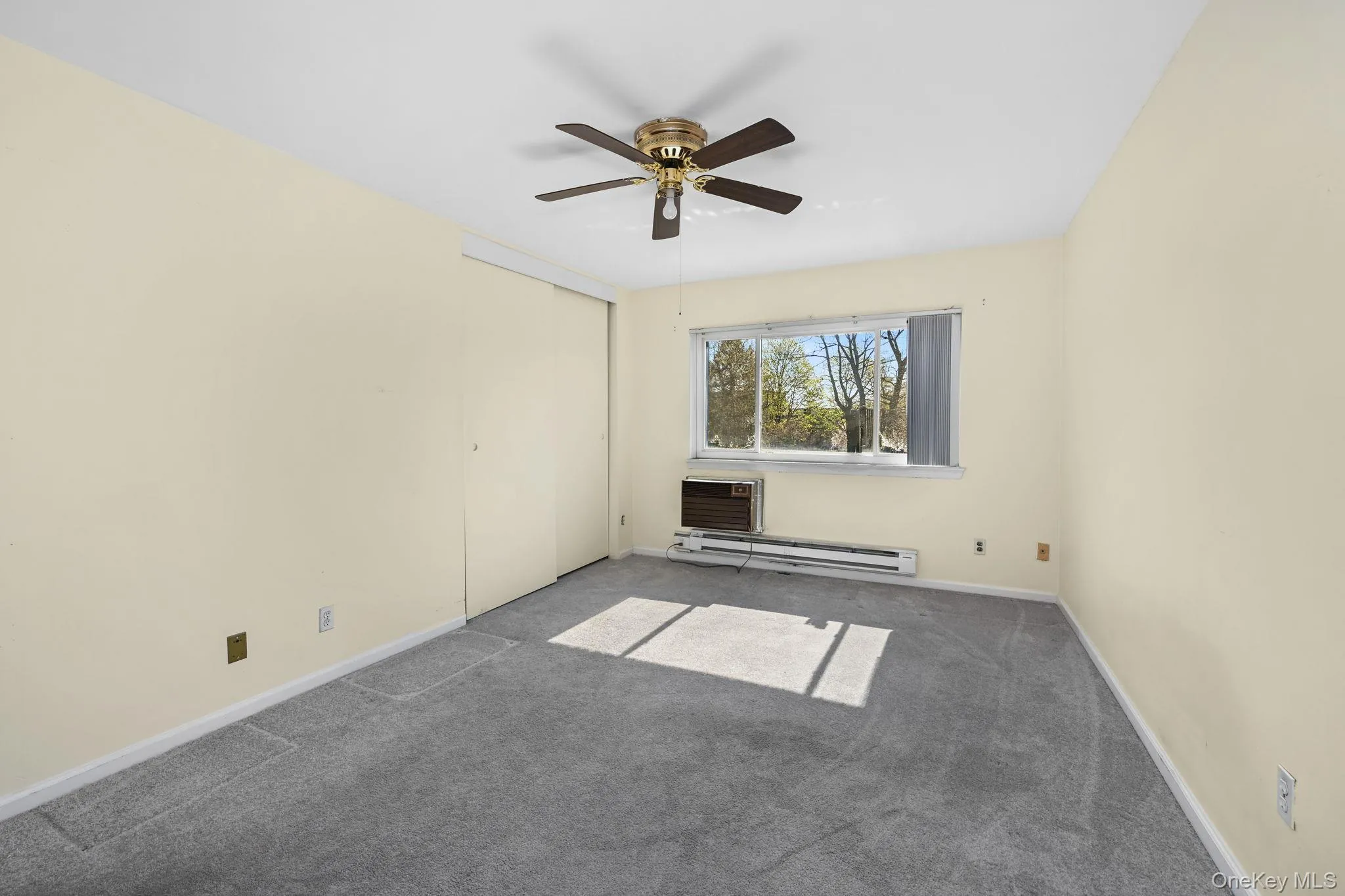 This room features light-colored walls, gray carpeting, and a ceiling fan This room features light-colored walls, gray carpeting, and a ceiling fan